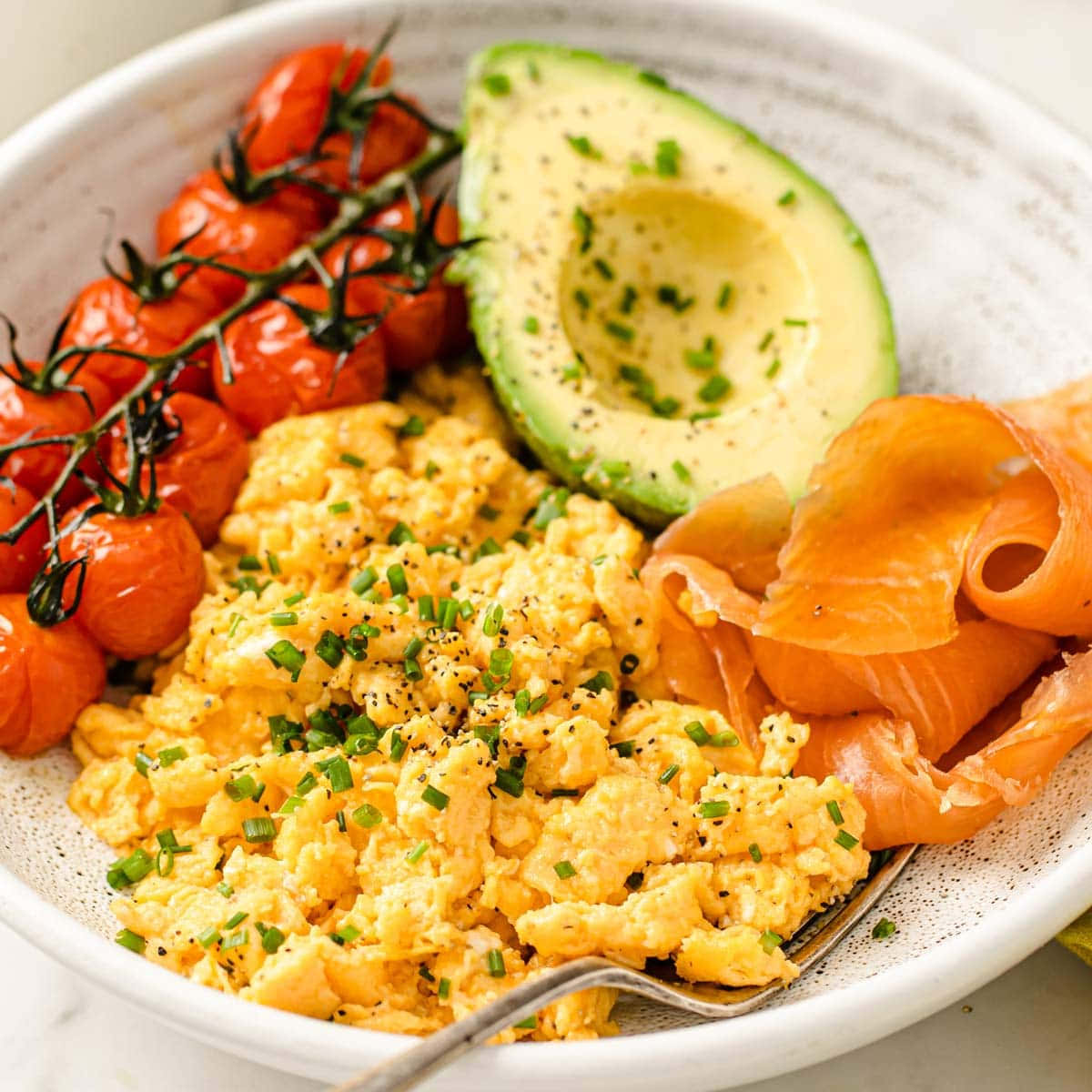 Scrambled Egg 桌布 壁紙 — 一個充滿活力的早餐碗，配有鬆軟炒蛋、烤櫻桃番茄、半個酪梨和煙燻鮭魚，並以細香蔥點綴。