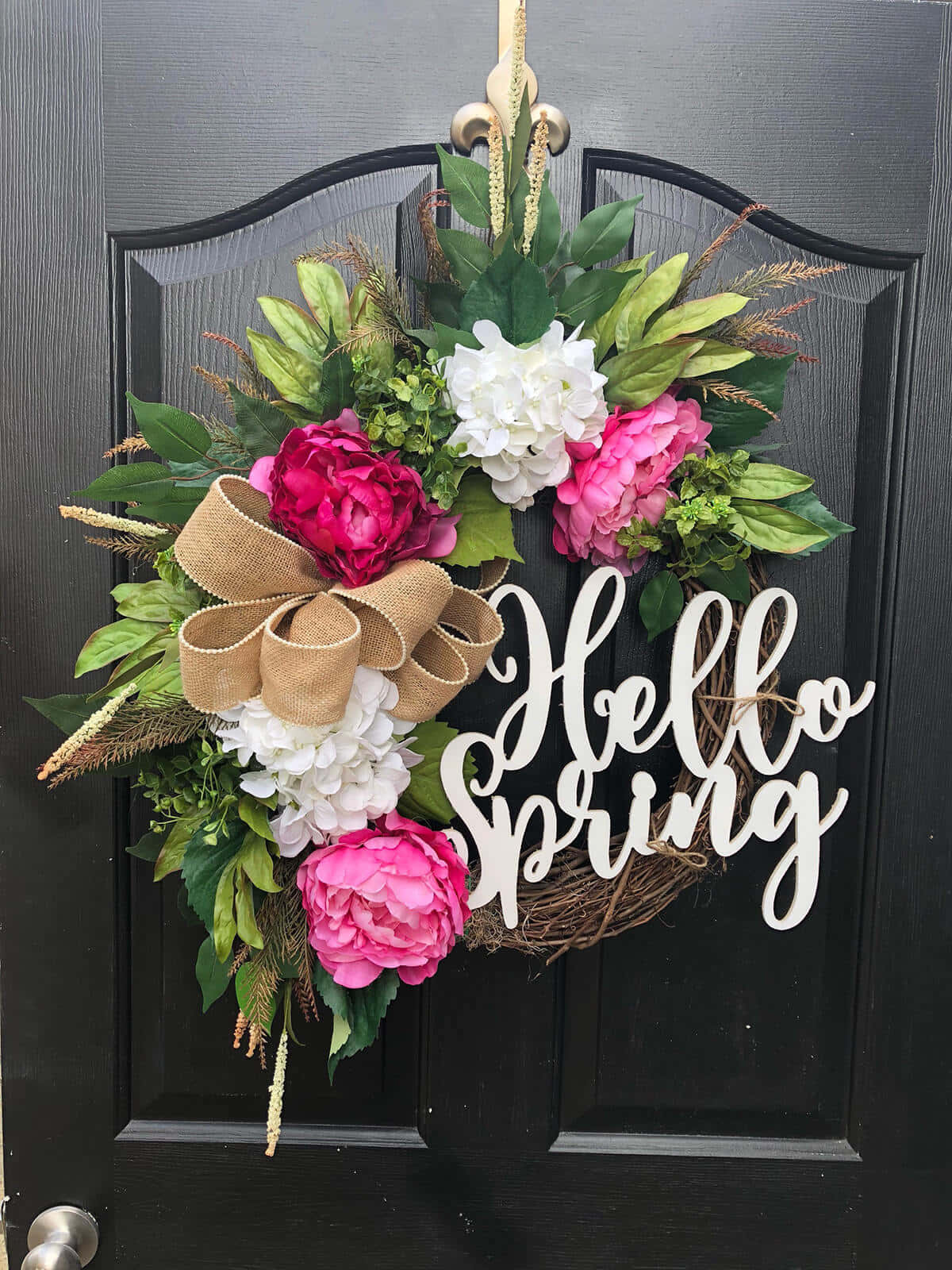 Spring Wreaths 桌布 壁紙 — 一個充滿活力的春天花環，飾有粉紅色牡丹、白色繡球花和一個麻布蝴蝶結，掛在深色木門上。