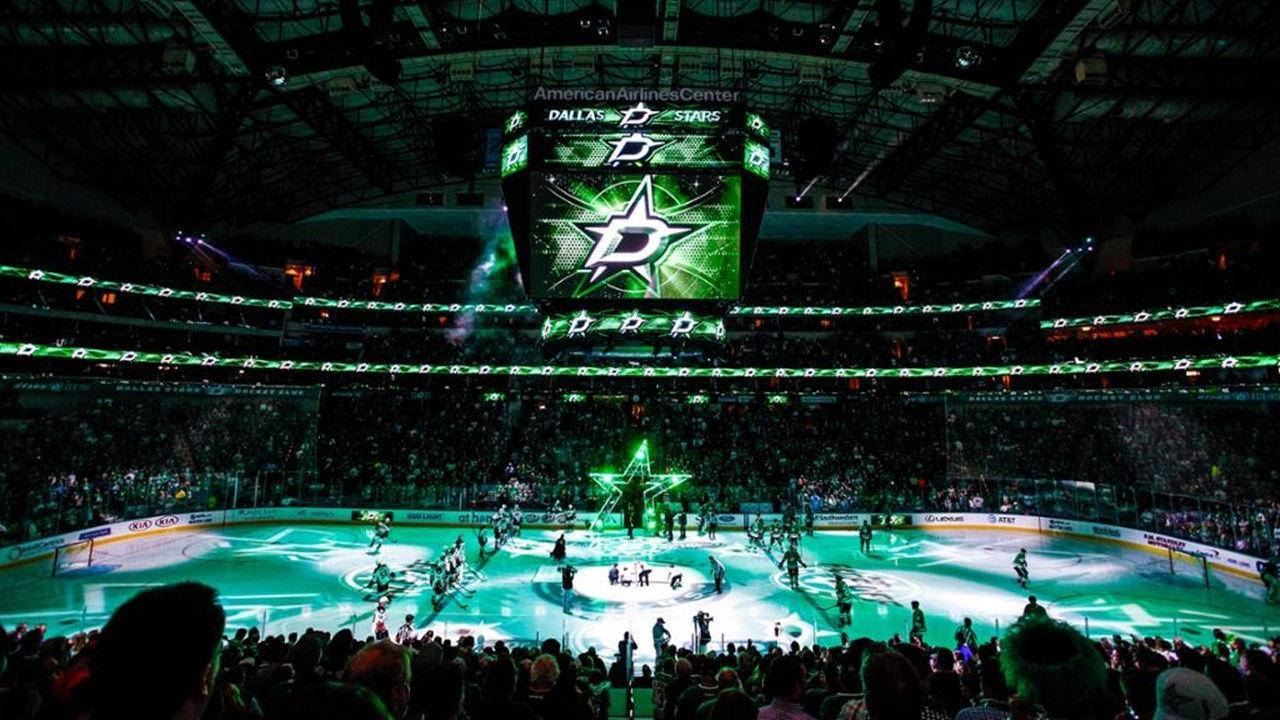 Dallas Stars 桌布 壁紙 — 一個充滿活力的曲棍球場，沐浴在綠色燈光中，球員們在巨大的達拉斯星隊記分板下滑行。