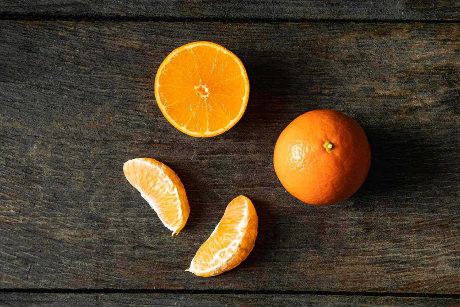 Fruits 桌布 壁紙 — 一個充滿活力的柳橙切成兩半，兩個瓣放在深色鄉村風木質表面上。
