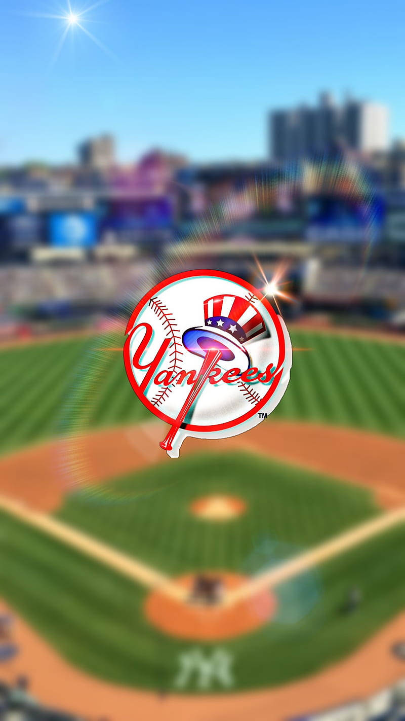 Yankees Logo 桌布 壁紙 — 一個充滿活力的棒球場，在晴朗的天空下，場地上方中央有一個發光的洋基隊標誌。
