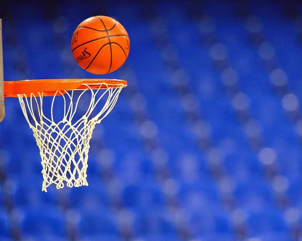 NBA 桌布 壁紙 — 一個充滿活力的橙色籃球完美地掛在白色網中，背景是模糊的藍色體育場。