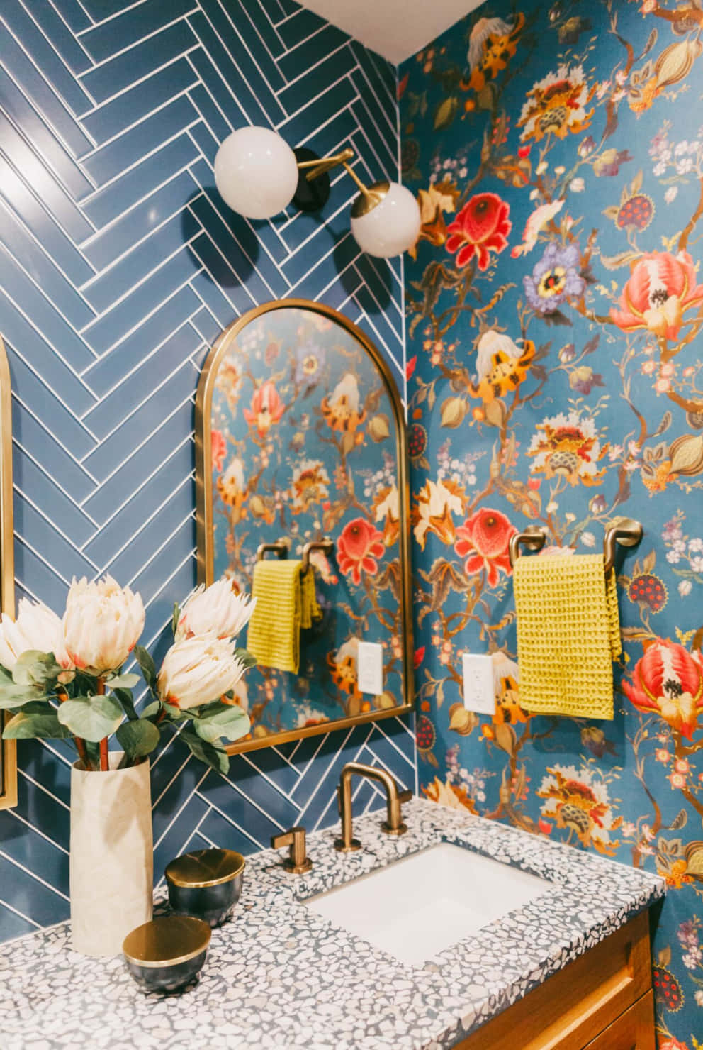 Bathroom Decor 桌布 壁紙 — 一個充滿活力的浴室，配有藍色人字形瓷磚牆和帶有鮮豔紅、橙、黃色花朵的花卉壁紙。