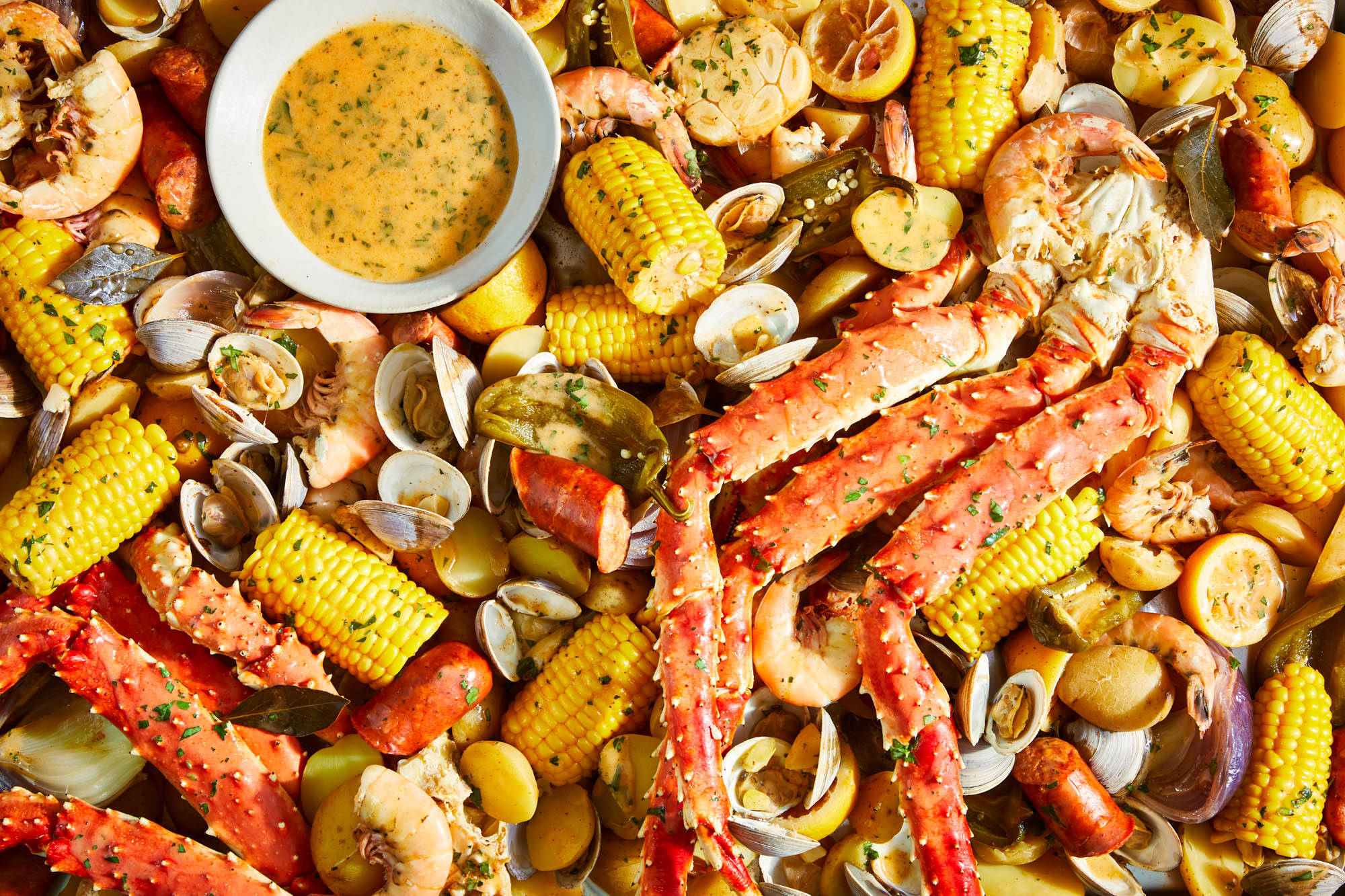 Seafood 桌布 壁紙 — 一個充滿活力的海鮮煮鍋特寫，包括蟹腳、蝦、玉米、蛤蜊和一碗奶油蘸醬。