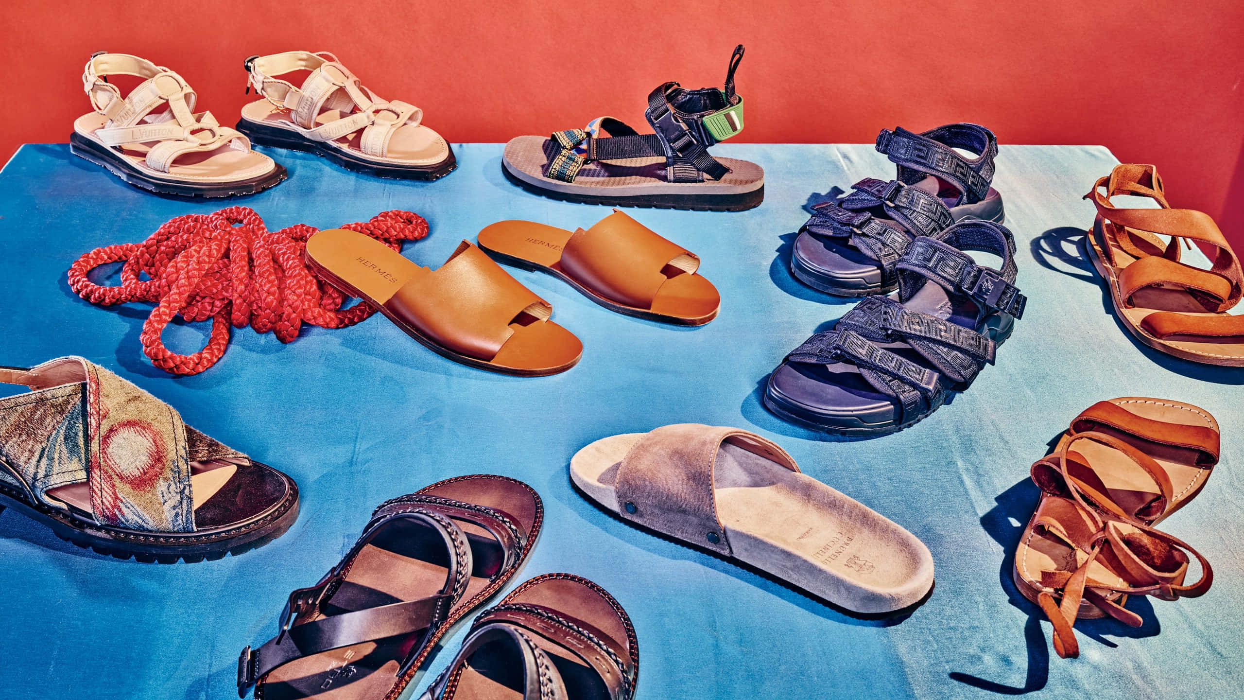 Beach Sandals 桌布 壁紙 — 一個充滿活力的涼鞋和繩索系列，排列在藍色布料上，背景是鮮明的紅色牆壁。