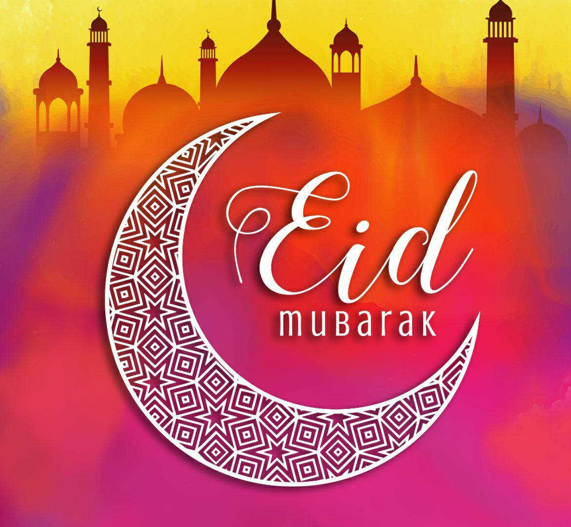Eid Mubarak 桌布 壁紙 — 一個充滿活力的漸變日落背景，裝飾性的新月帶有複雜圖案，並在剪影的清真寺圓頂和宣禮塔上方顯示「Eid Mubarak」文字。