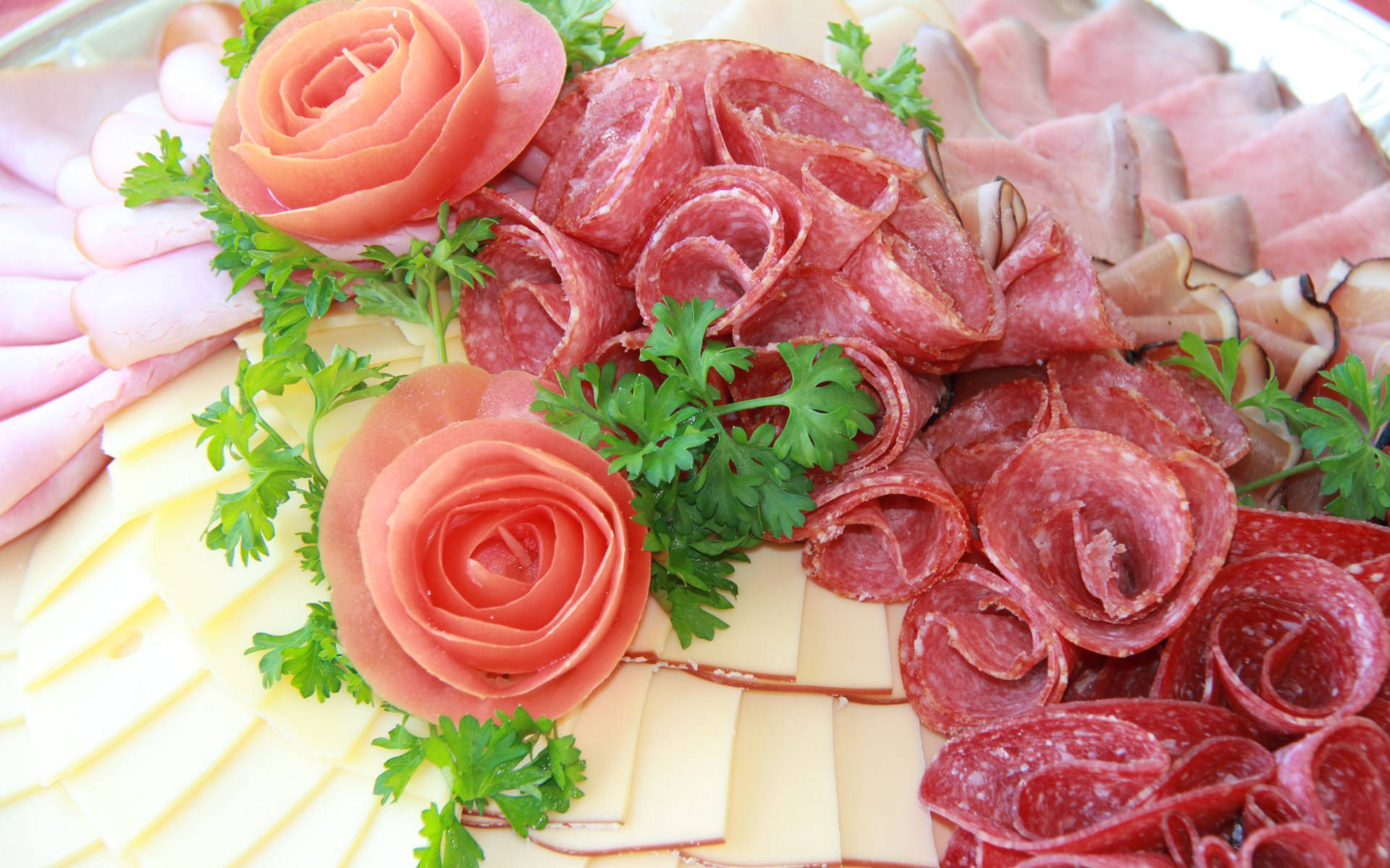 meat 桌布 壁紙 — 一個充滿活力的熟食拼盤，藝術地擺放著玫瑰形狀的火腿、切片薩拉米、起司和新鮮歐芹。