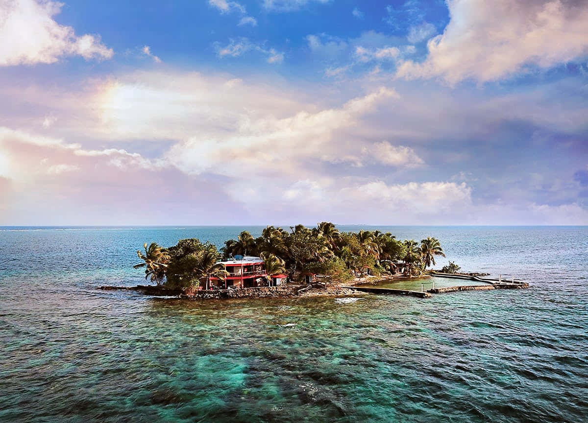 Caribbean Island 桌布 壁紙 — 一個充滿活力的熱帶島嶼，擁有茂密的棕櫚樹和紅頂別墅，坐落在水晶般清澈的碧綠海水中，上方是戲劇性的多雲天空。