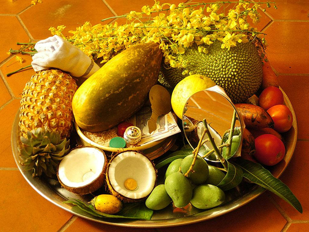 Vishu 桌布 壁紙 — 一個充滿活力的熱帶水果拼盤，有鳳梨、波羅蜜、芒果和黃色花朵，排列在赤陶磚表面上。