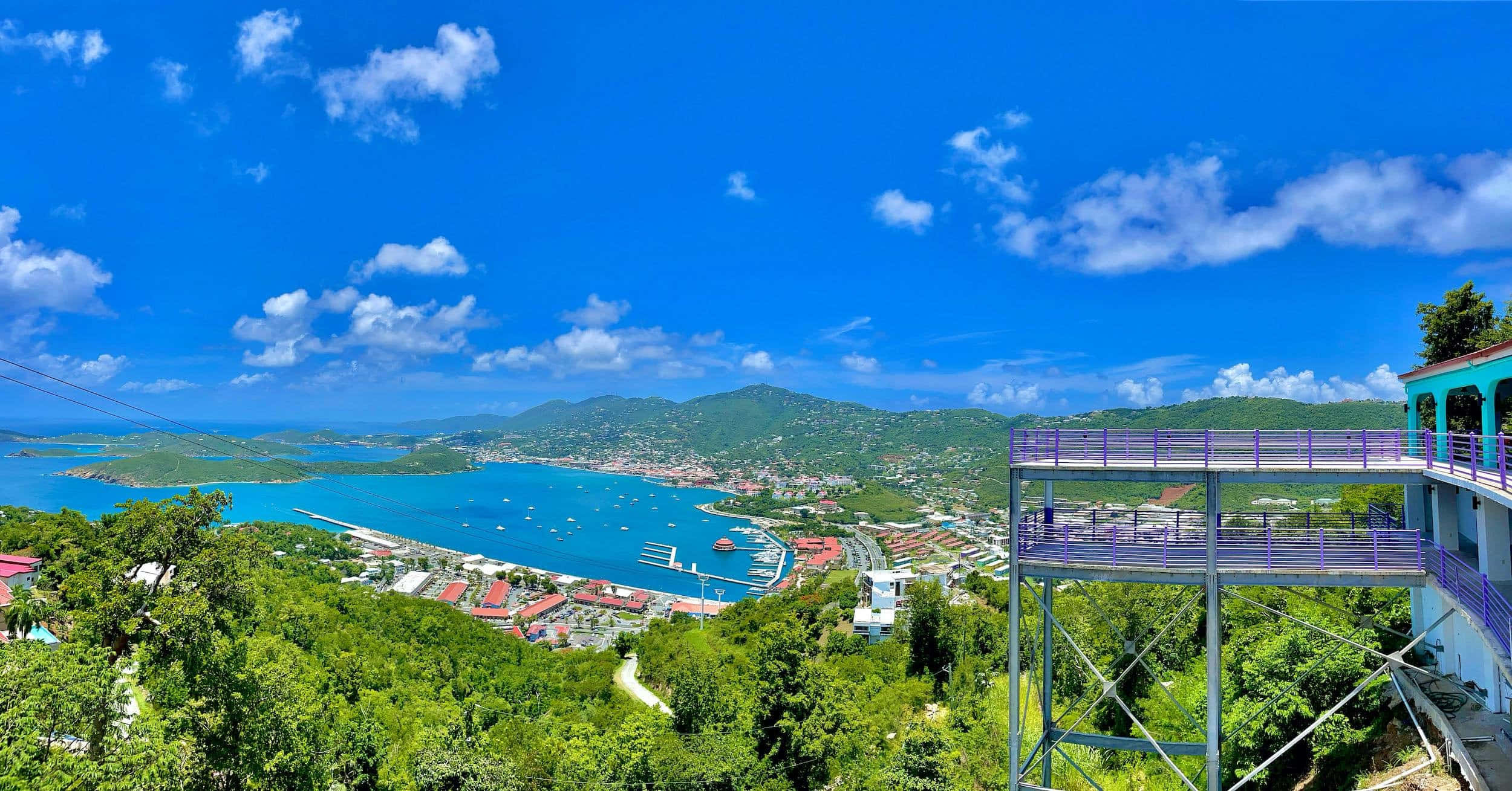 paradise 桌布 壁紙 — 一個充滿活力的熱帶海灣，擁有碧綠的海水和鬱鬱蔥蔥的綠色山丘，在明亮的藍天下點綴著蓬鬆的白雲。