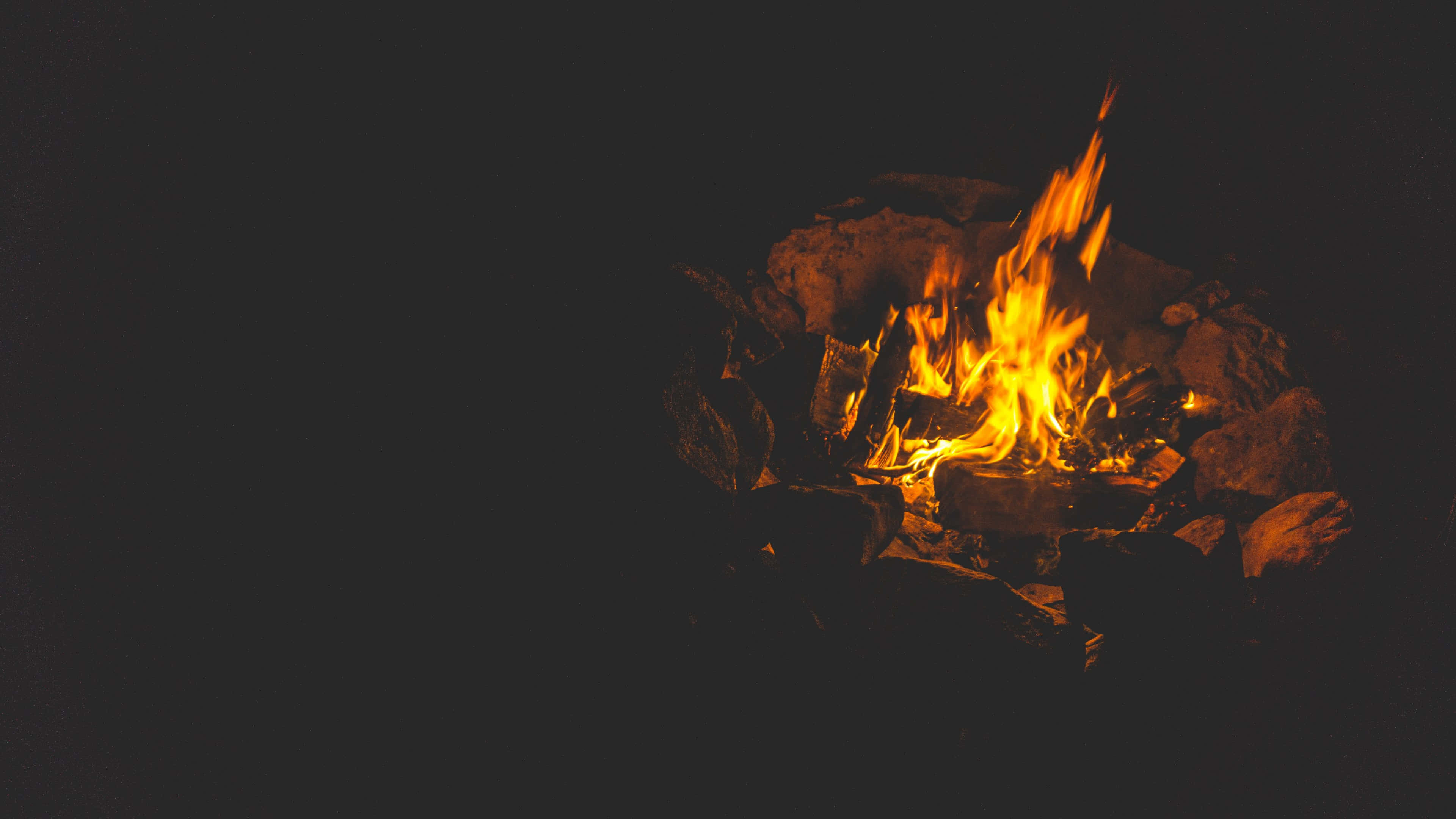 Fall Bonfire 桌布 壁紙 — 一個充滿活力的營火在漆黑的夜空中劈啪作響，橙色的火焰翩翩起舞。