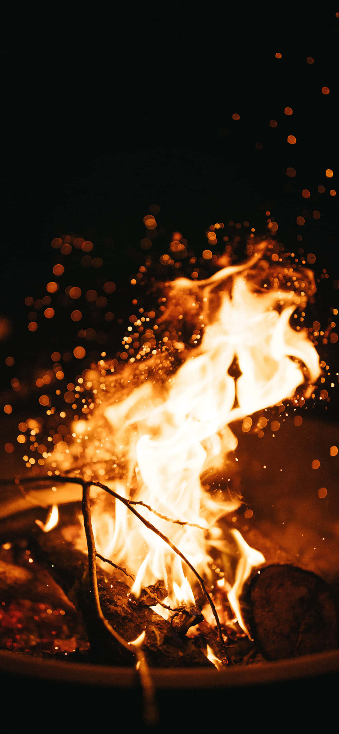 Fall Bonfire 桌布 壁紙 — 一個充滿活力的營火在黑暗的夜空中噼啪作響，閃爍著金色的火焰和發光的餘燼。