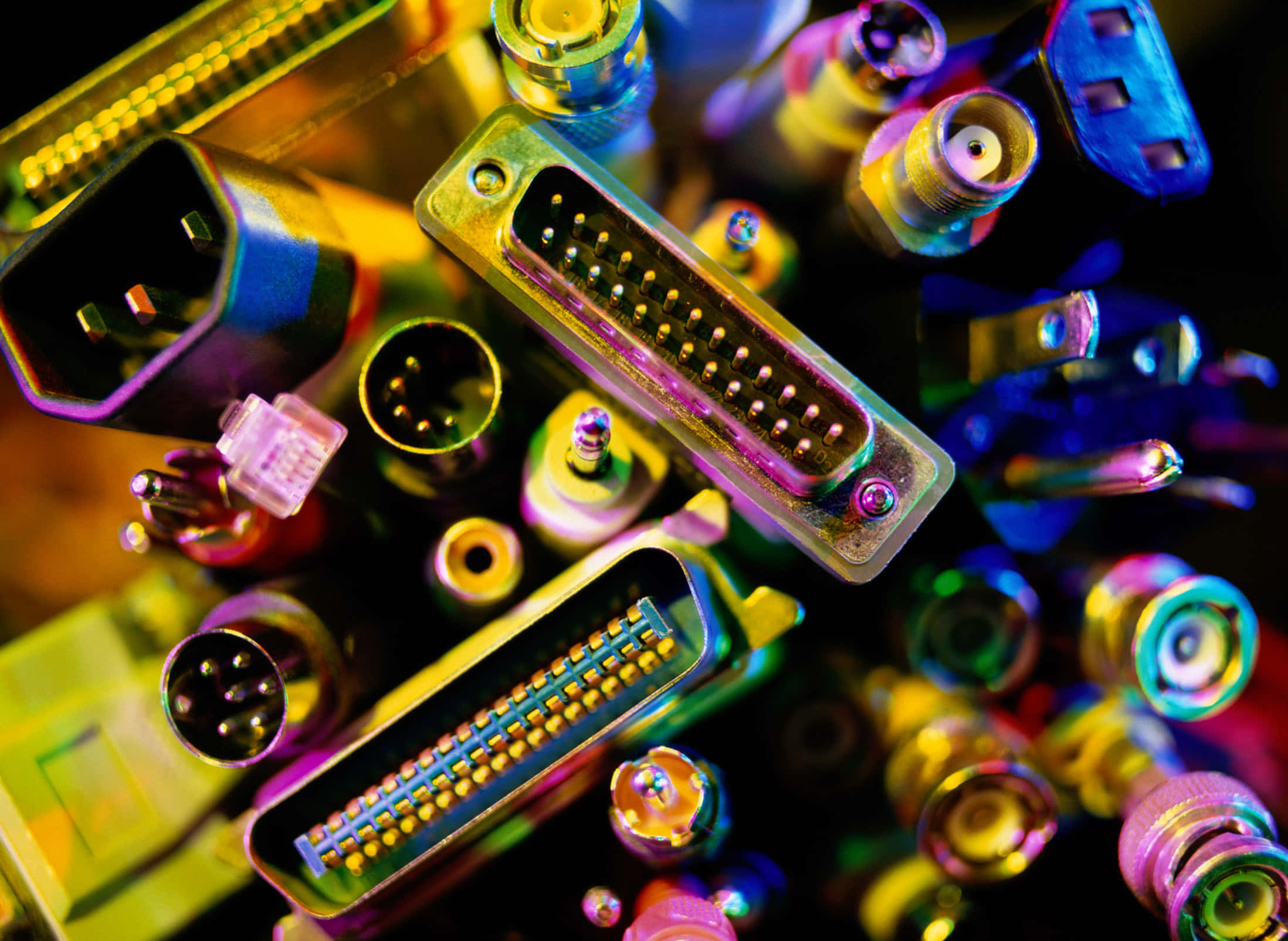 Electronic Components 桌布 壁紙 — 一個充滿活力的特寫，各種彩色電子連接器在黑暗背景下的霓虹燈光中發光。