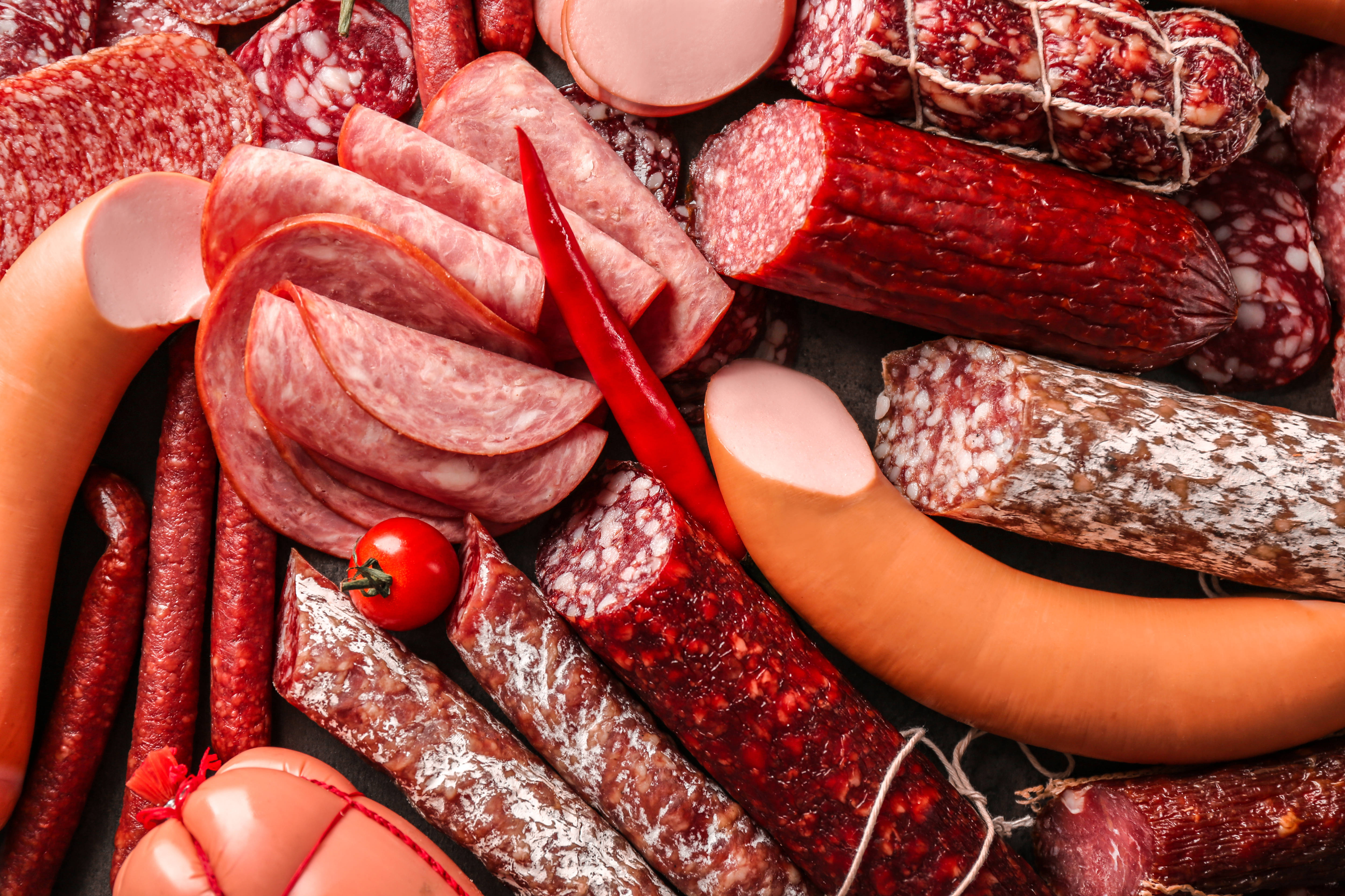 meat 桌布 壁紙 — 一個充滿活力的特寫，展示各種醃製肉類和一個紅辣椒，排列在深色表面上。