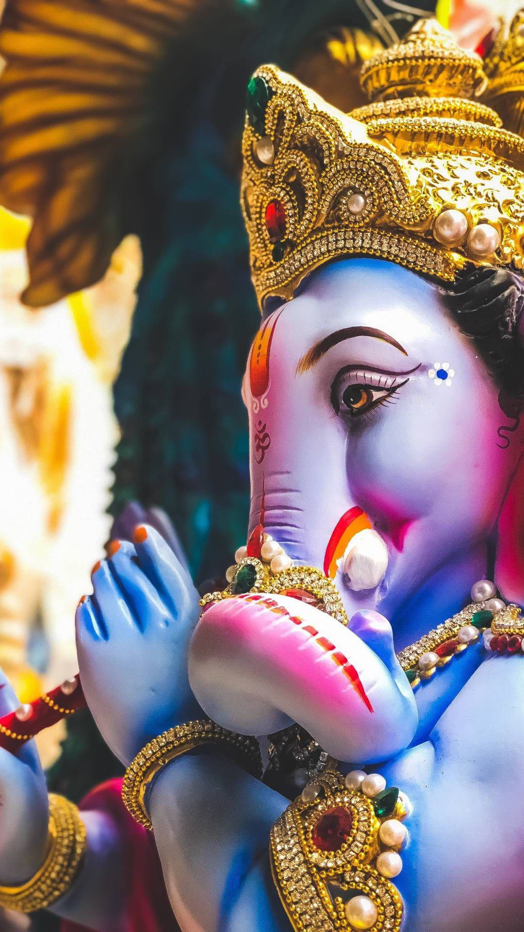 Ganesh 桌布 壁紙 — 一個充滿活力的特寫，描繪藍皮膚的印度教神祇象頭神，飾有金色珠寶和彩色寶石。