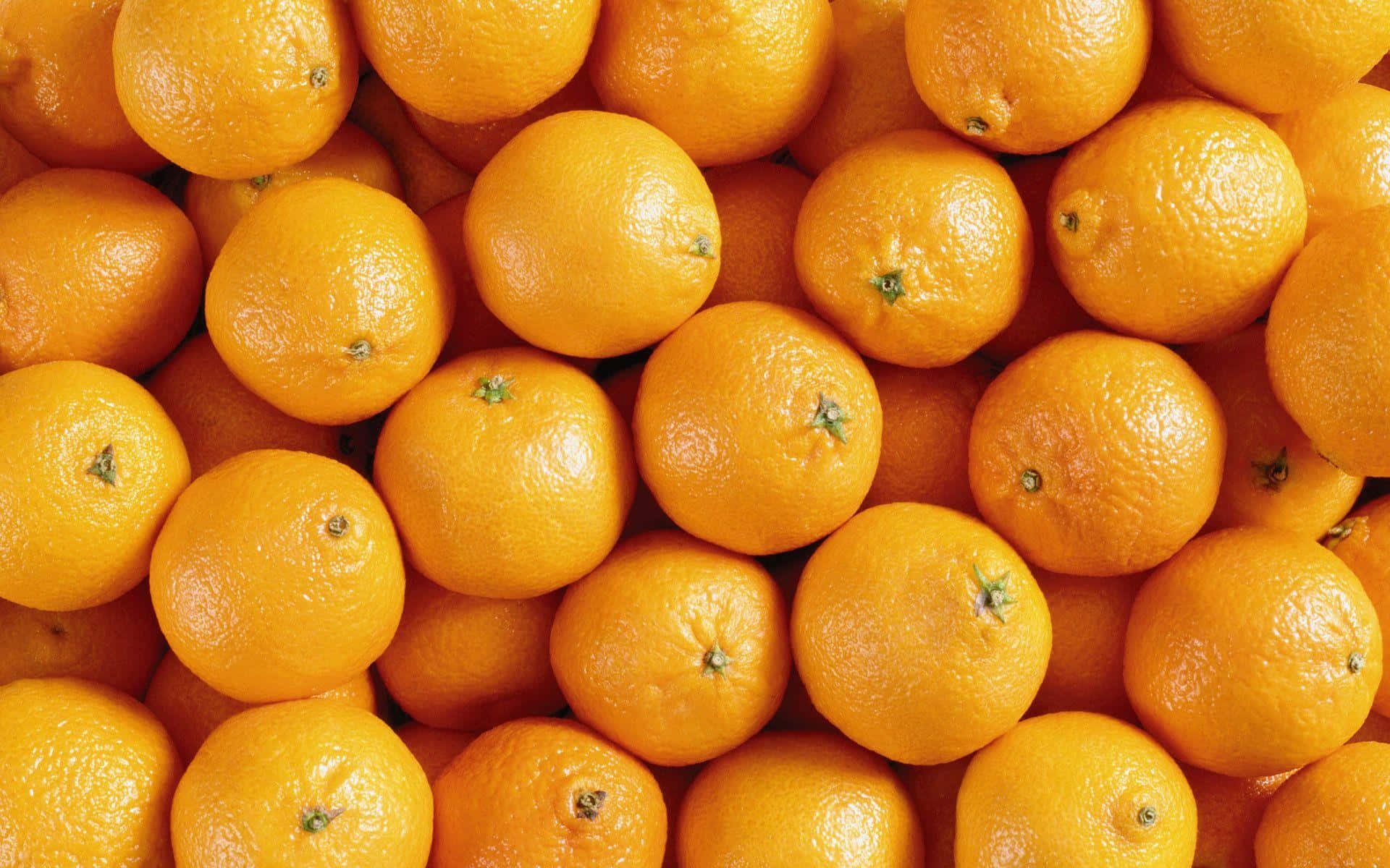 Orange Fruit 桌布 壁紙 — 一個充滿活力的特寫，新鮮柳橙堆疊在一起，展示它們有紋理的果皮和明亮的橙色色調。