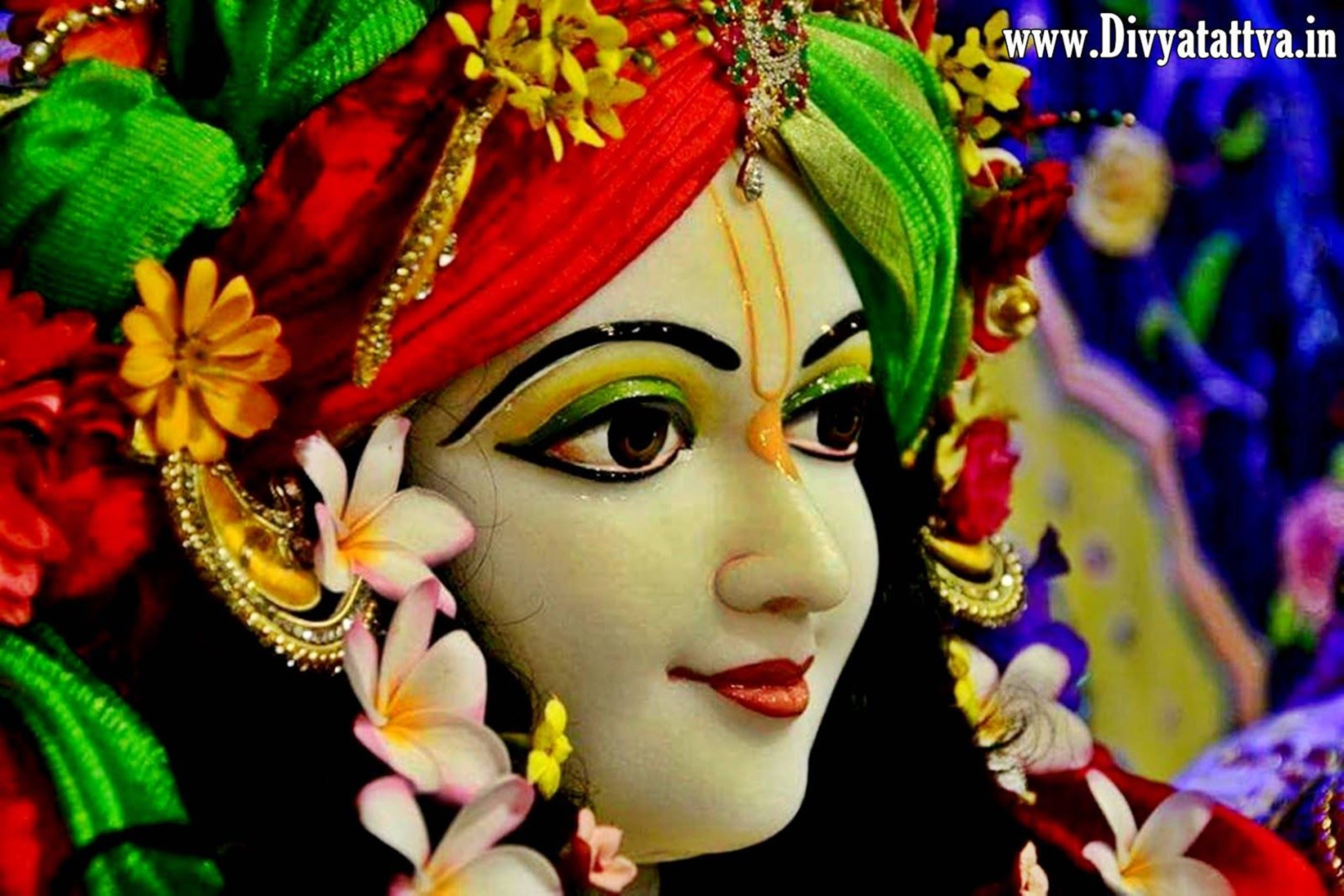 krishna god 桌布 壁紙 — 一個充滿活力的特寫鏡頭，描繪一位神聖的女性神祇，裝飾著紅綠相間的花朵、黃金首飾和粉紅色的雞蛋花。