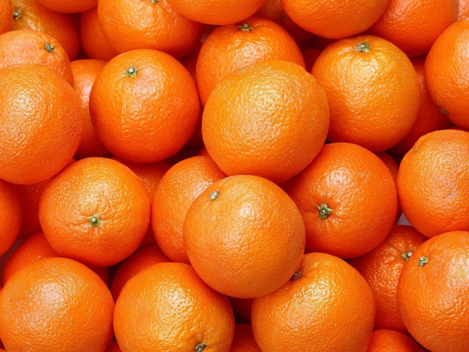 Orange Fruit 桌布 壁紙 — 一個充滿活力的特寫鏡頭，新鮮柳橙堆疊在一起，展示它們帶有紋理的果皮和明亮的橙色色調。