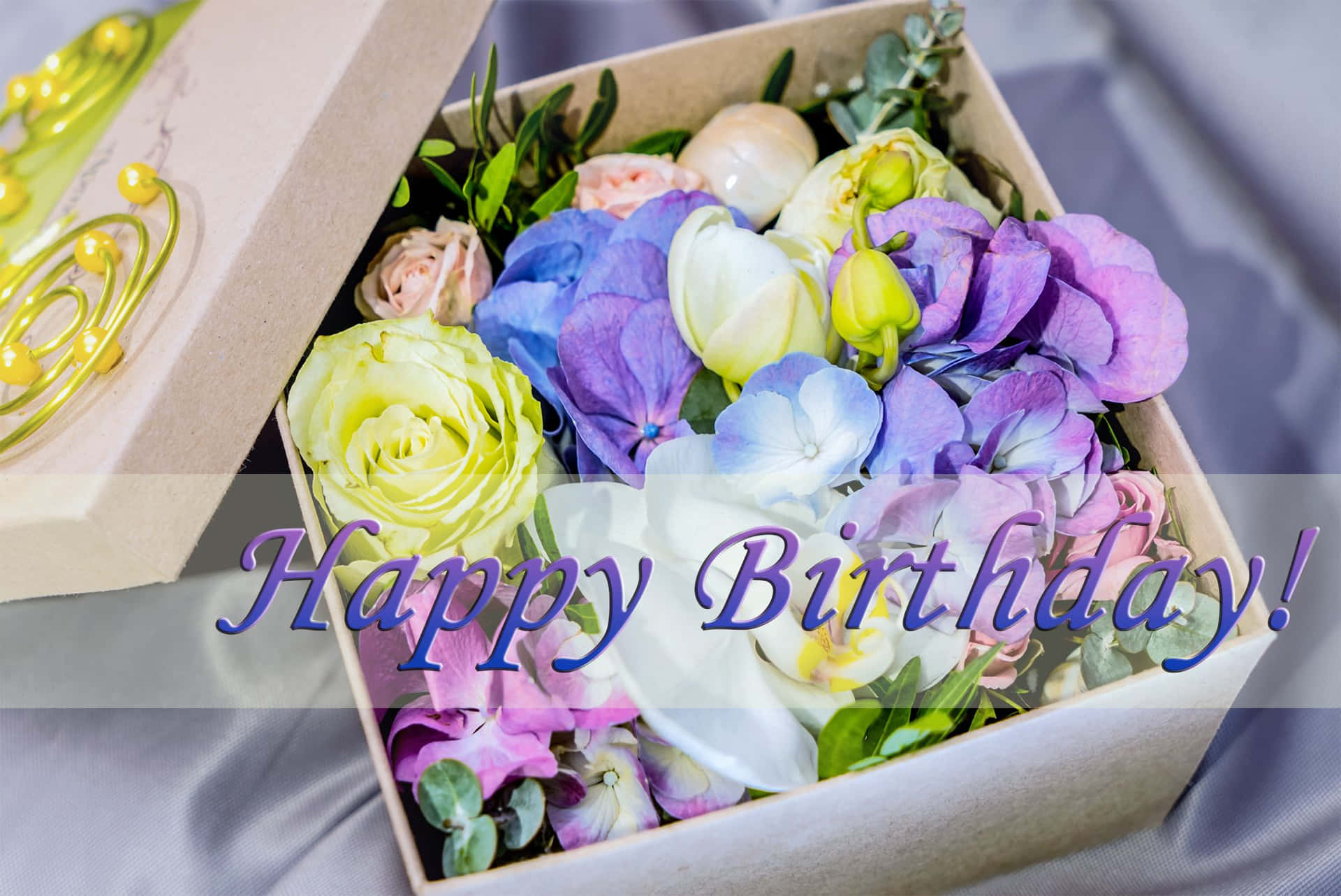 生日快樂 桌布 壁紙 — 一個充滿活力的生日花束，包含紫色、藍色和黃色的花朵，放在米色盒子中，並帶有慶祝訊息覆蓋。