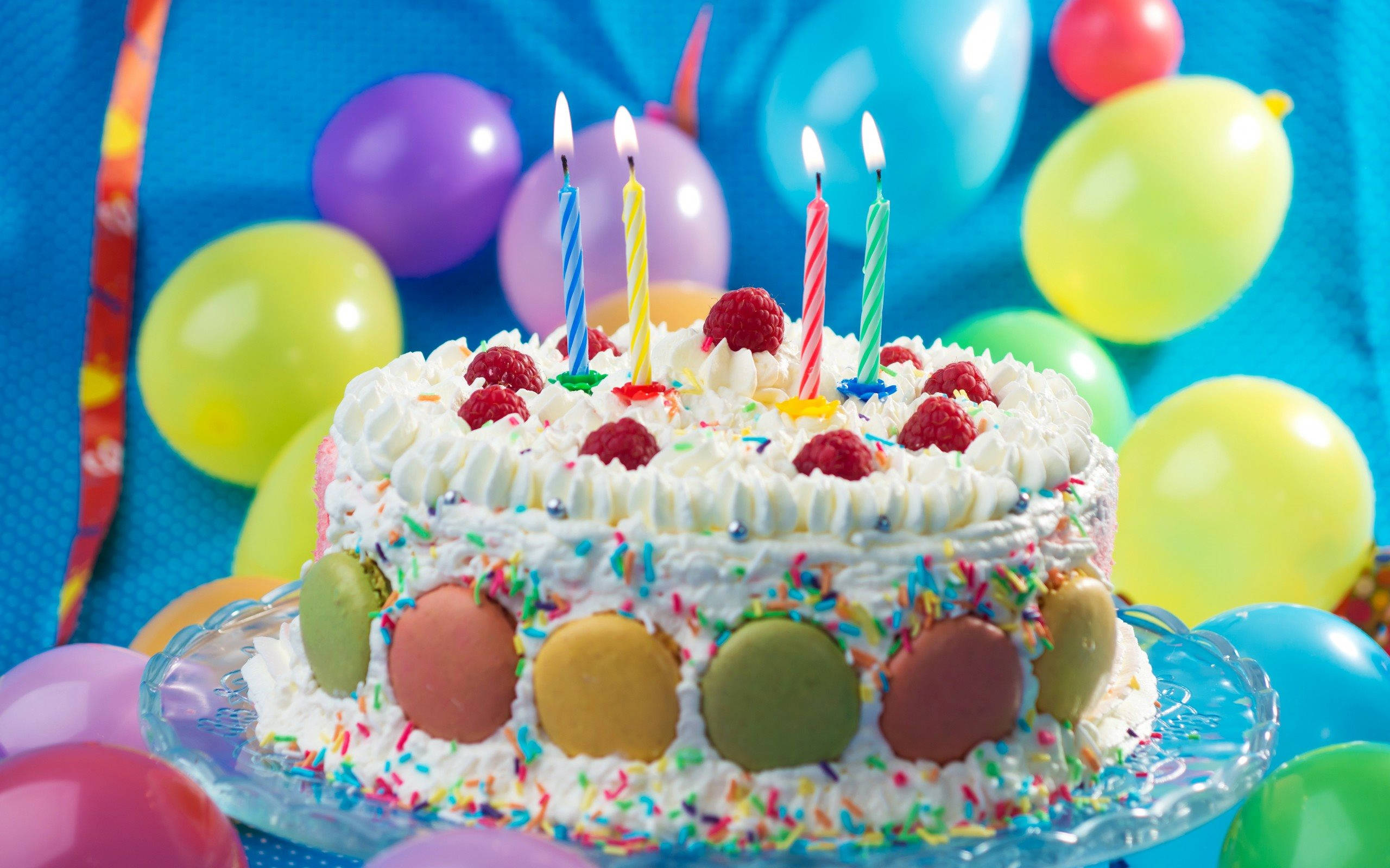 Cake 桌布 壁紙 — 一個充滿活力的生日蛋糕，上面有覆盆子、點燃的蠟燭和色彩繽紛的馬卡龍，周圍環繞著節日氣球。
