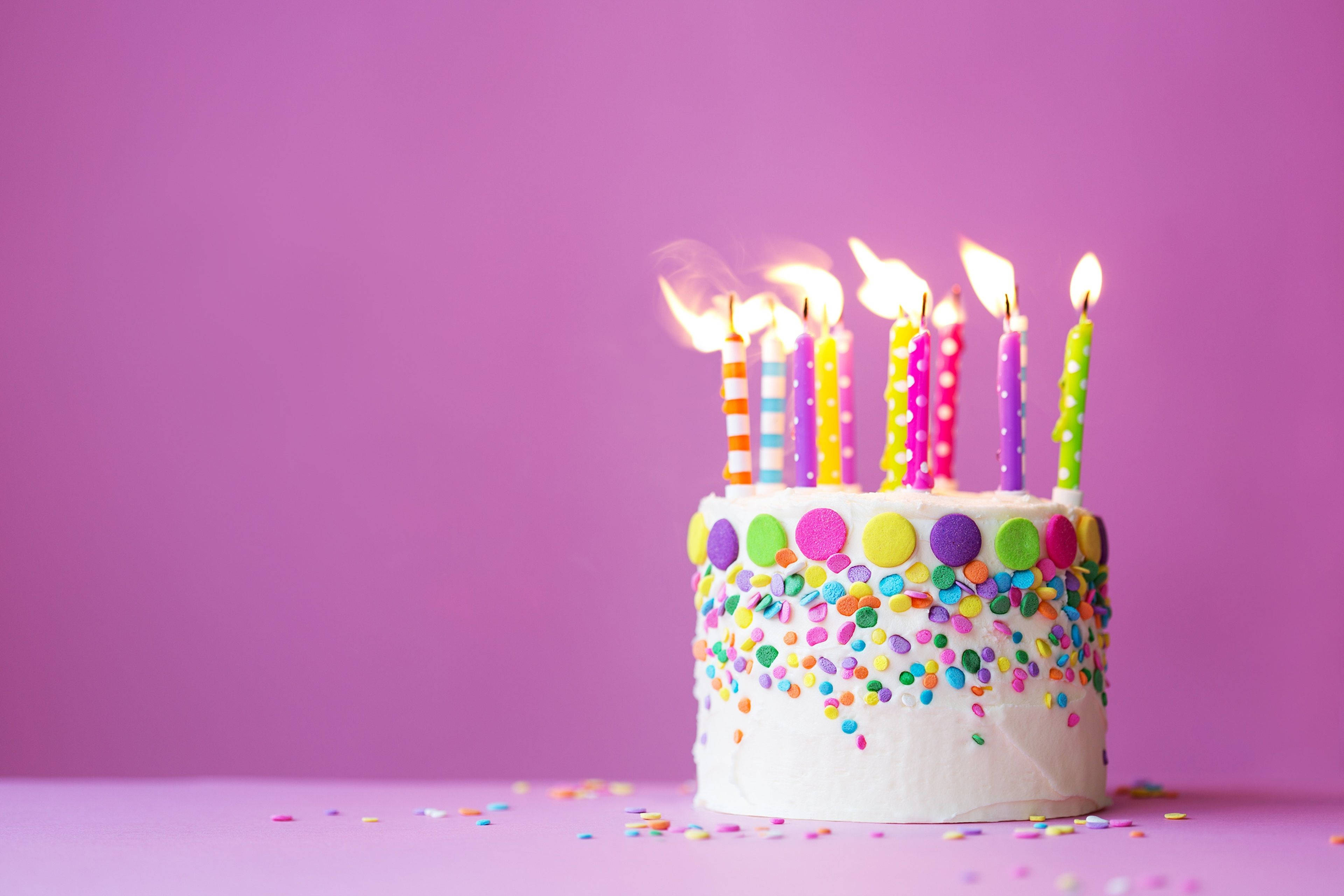 Cake 桌布 壁紙 — 一個充滿活力的生日蛋糕，帶有彩色蠟燭和糖霜，背景為純紫色。