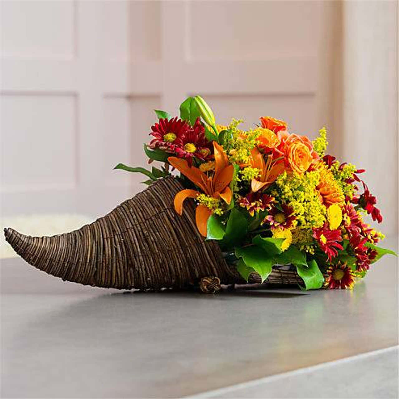 Fall Cornucopia 桌布 壁紙 — 一個充滿活力的秋季花卉佈置從一個編織的豐收角中溢出，放在一個光滑的檯面上。