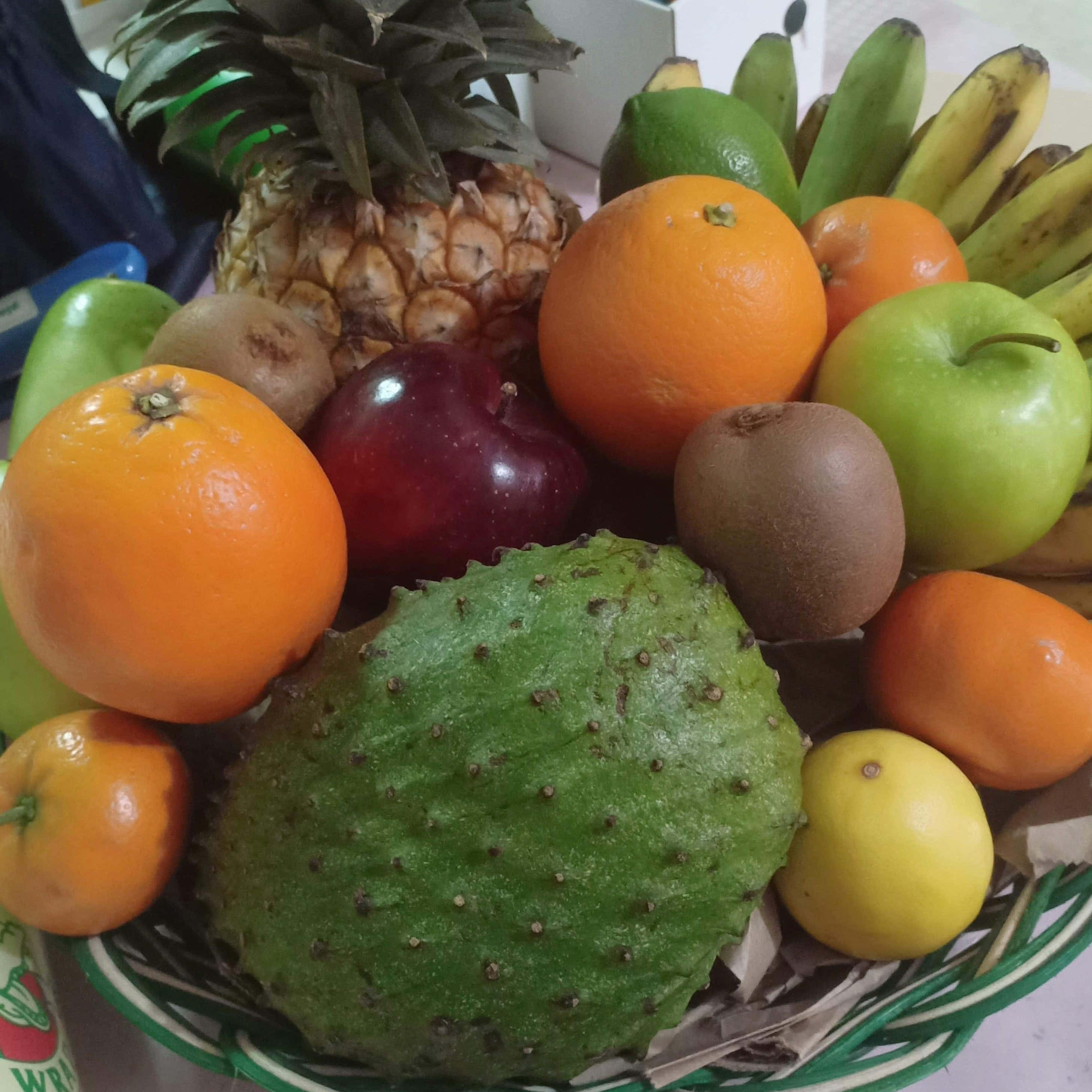 水果籃 桌布 壁紙 — 一個充滿活力的籃子，裝滿了各種新鮮水果，包括鳳梨、柳橙、蘋果、奇異果和香蕉。