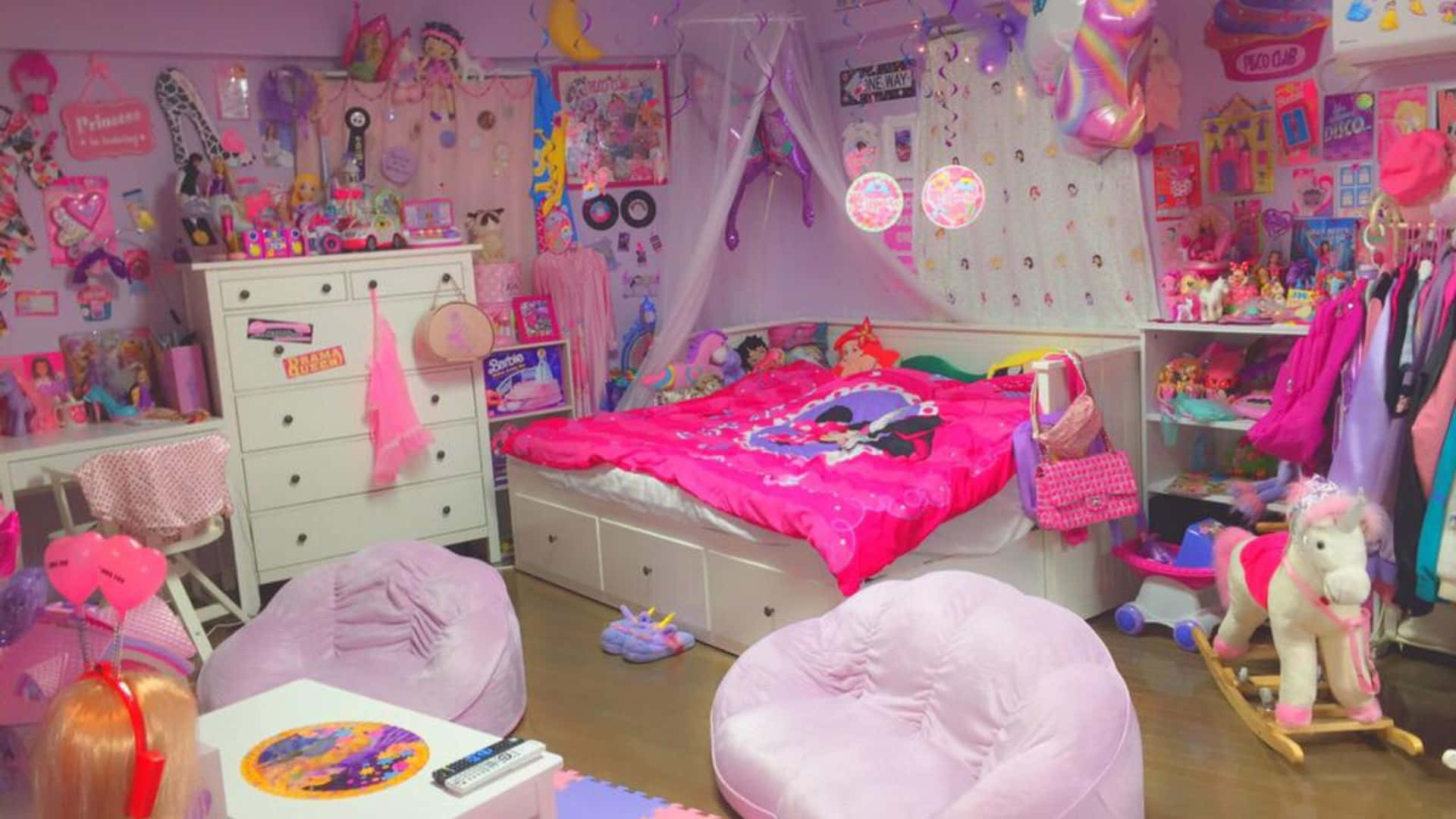 Kawaii Room 桌布 壁紙 — 一個充滿活力的粉紅色主題女孩臥室，裡面有毛絨豆袋椅、玩具、海報和一張裝飾著閃亮裝飾的華蓋床。