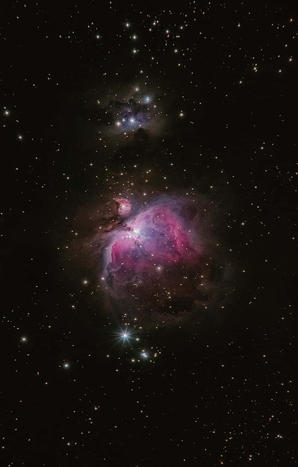 星光點亮的謎樣黑暗星系 壁紙 — 一個充滿活力的粉紅色和紫色星雲在深空的星場中發光。