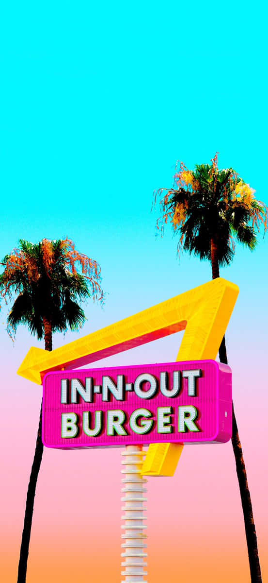 In N Out 桌布 壁紙 — 一個充滿活力的粉紅色和黃色In-N-Out Burger霓虹招牌高高聳立，背景是漸變色的天空，棕櫚樹框住了整個場景。