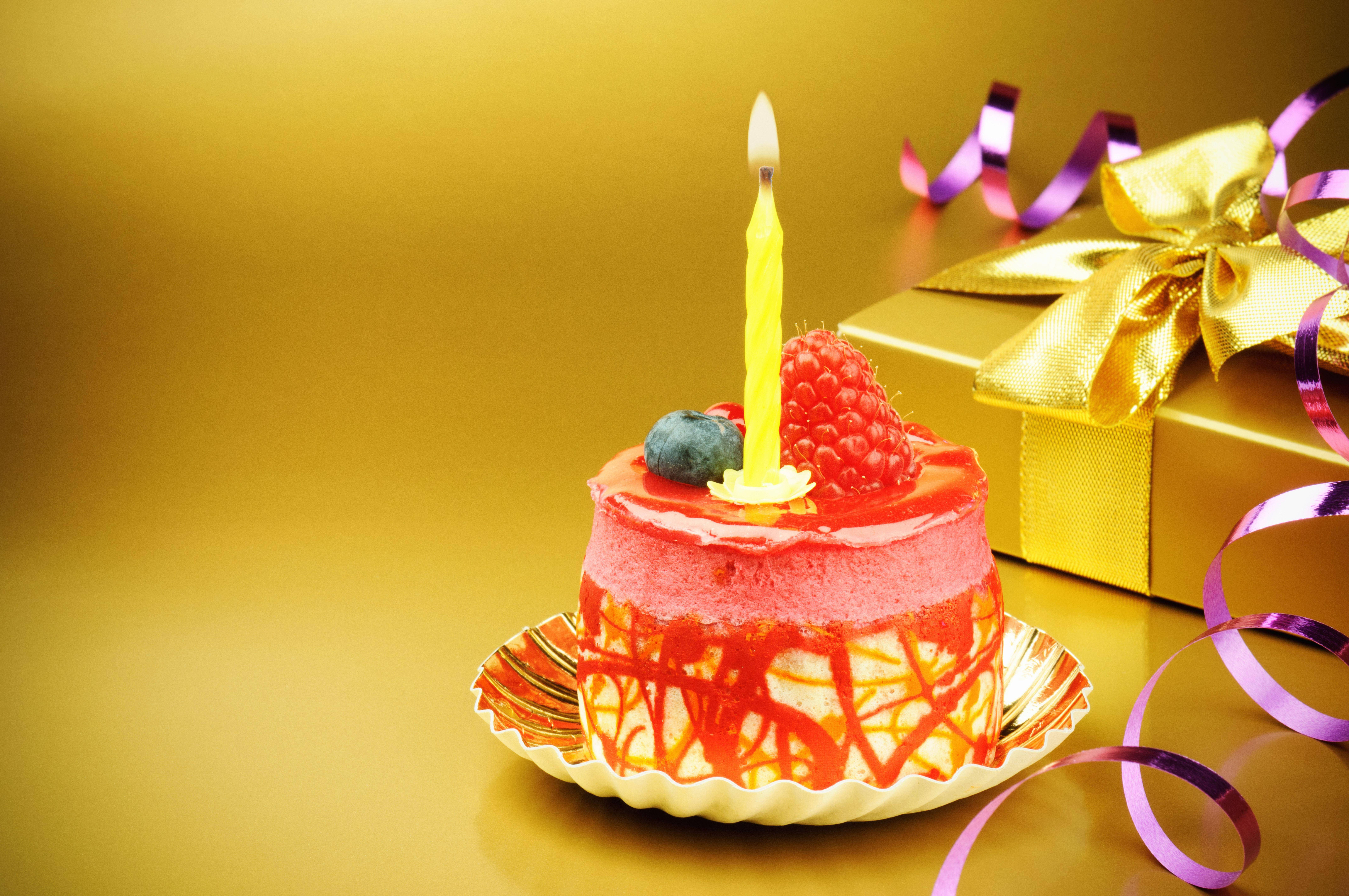 my 桌布 壁紙 — 一個充滿活力的粉紅色生日蛋糕，上面有燃燒的黃色蠟燭和新鮮莓果，旁邊是一個金色禮物盒，裝飾著紫色絲帶。