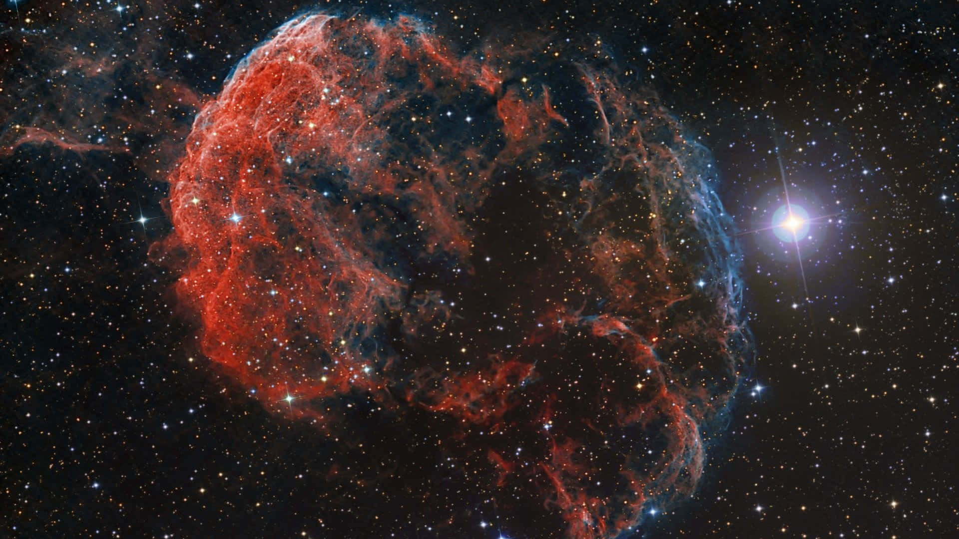 Nasa Galaxy 桌布 壁紙 — 一個充滿活力的紅色和藍色星雲在星空中旋轉，附近有一顆明亮的星星閃耀。