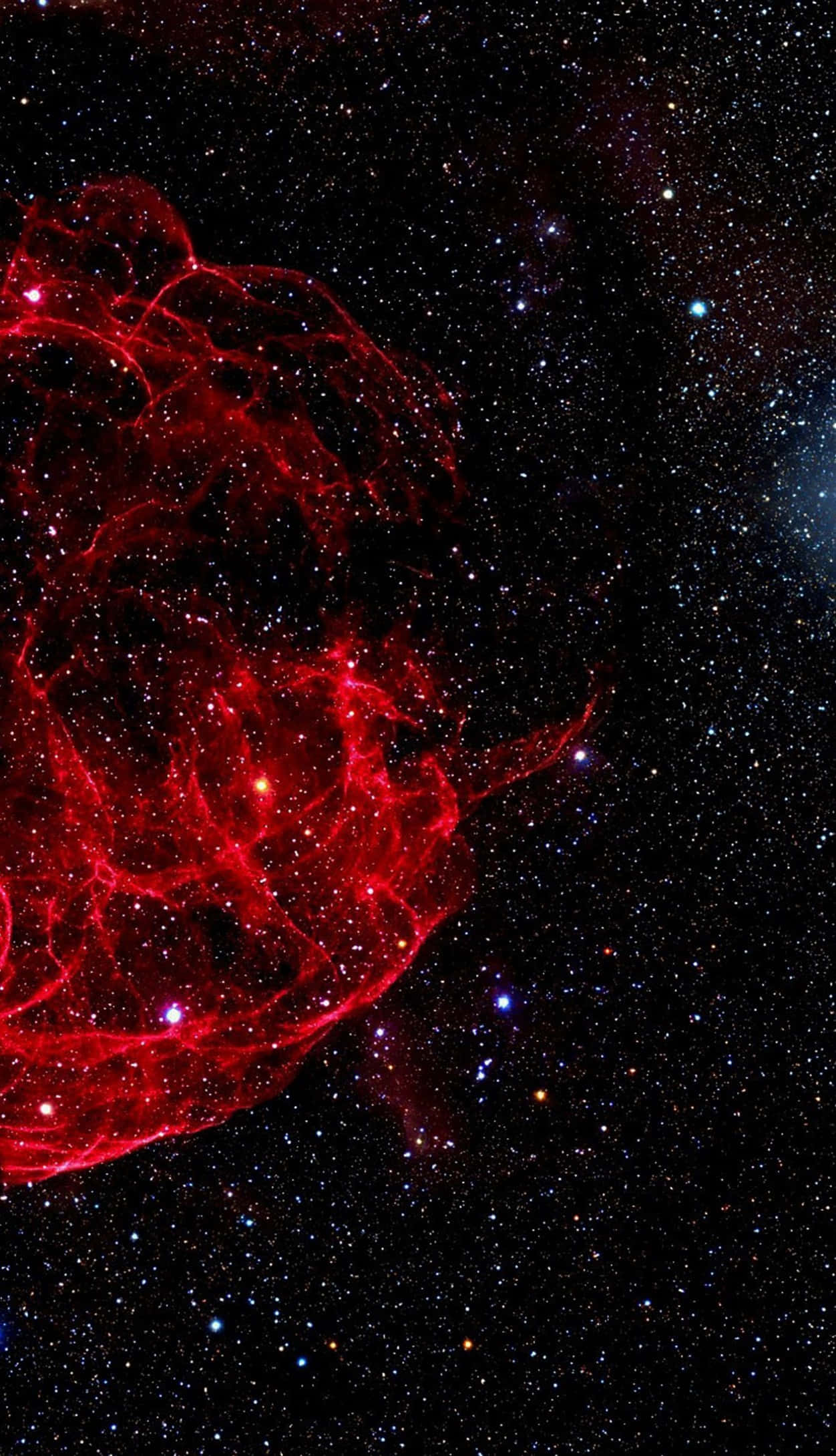 桌布 壁紙 — 一個充滿活力的紅色星雲在深空中旋轉，背景是散落的藍色和白色星星。
