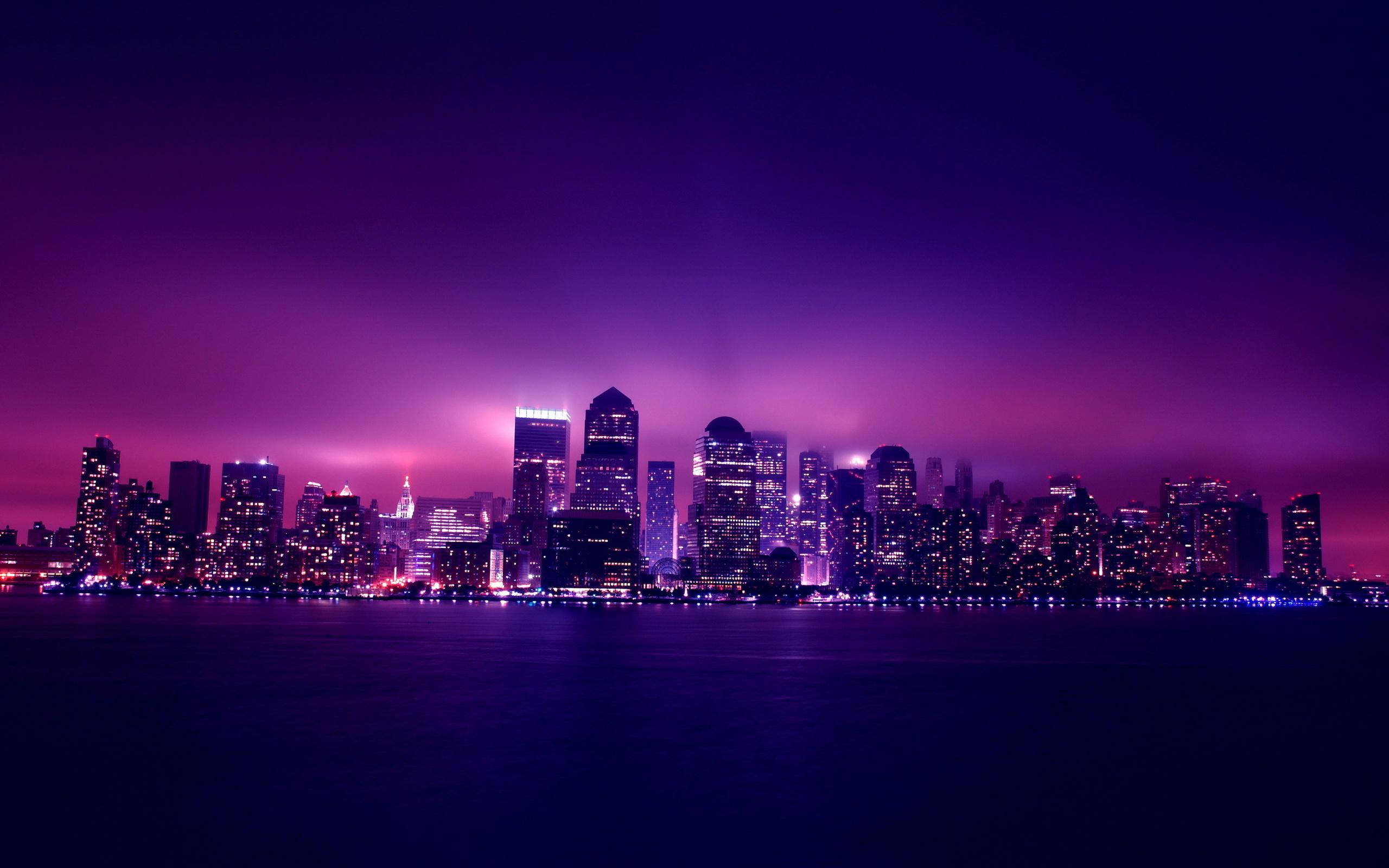 夜景城市 桌布 壁紙 — 一個充滿活力的紫色暮色城市天際線，發光的摩天大樓倒映在平靜的水面上。