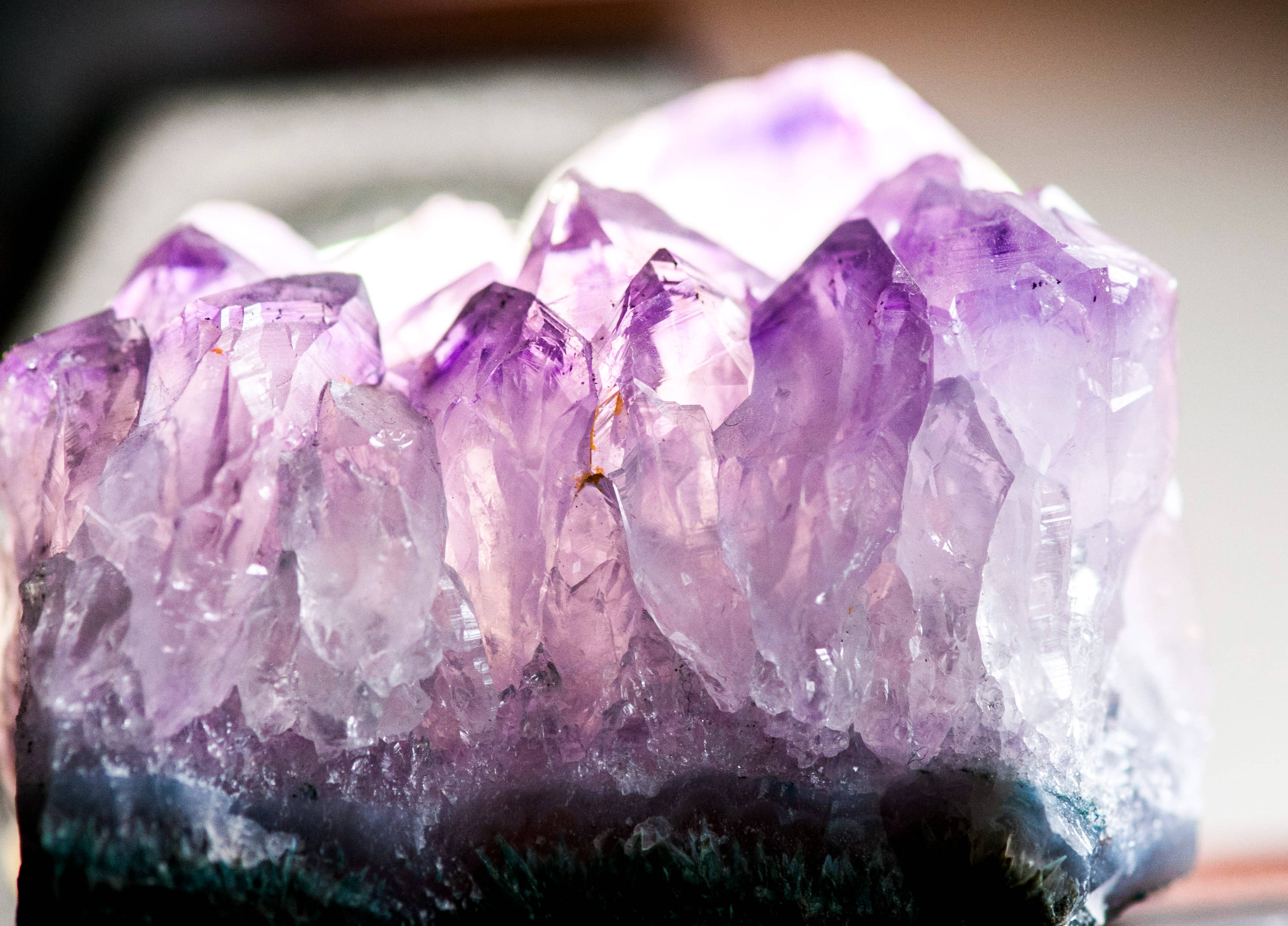 紫水晶 桌布 壁紙 — 一個充滿活力的紫色紫水晶晶體簇的特寫，具有銳利的刻面和深色底座。