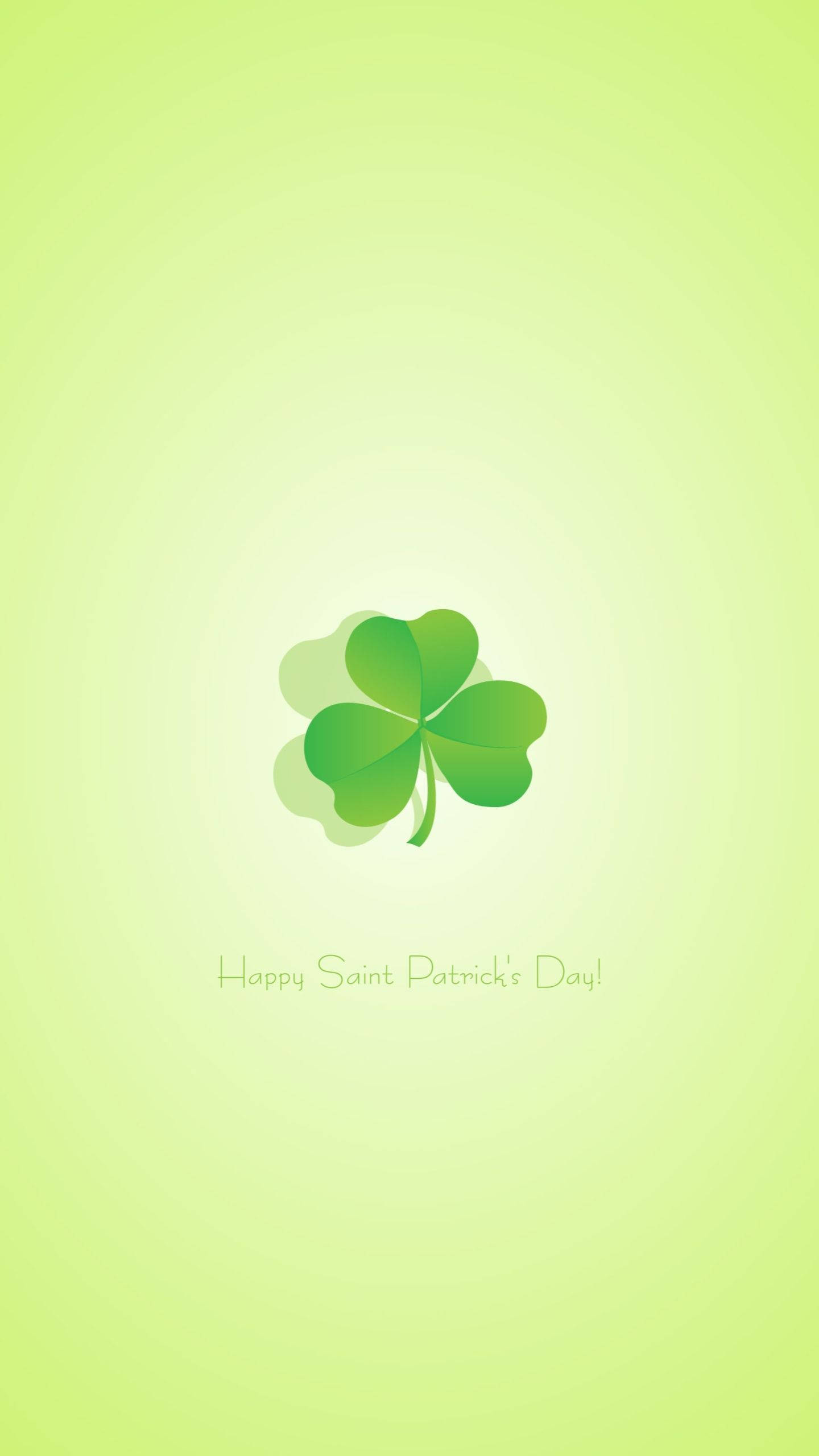 St Patrick's Day 桌布 壁紙 — 一個充滿活力的綠色四葉草居中在柔和的漸變背景上，下方有節日的聖派翠克節祝福語。
