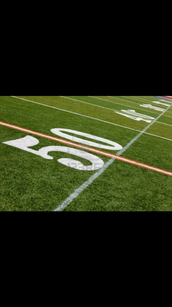 Android Football 桌布 壁紙 — 一個充滿活力的綠色足球場的特寫，帶有粗體白色油漆的數字50和橙色碼線。