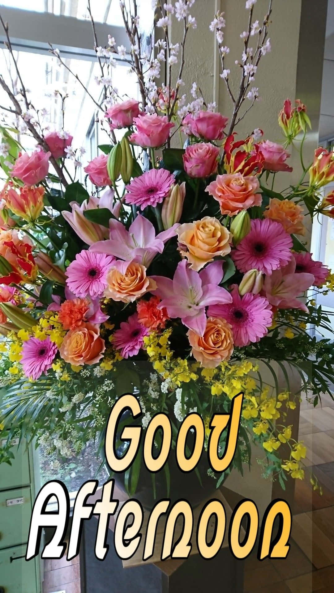 Good Afternoon 桌布 壁紙 — 一個充滿活力的花卉佈置，包含粉紅玫瑰、百合和黃色花朵，放在花瓶中，並帶有'下午好'的文字。