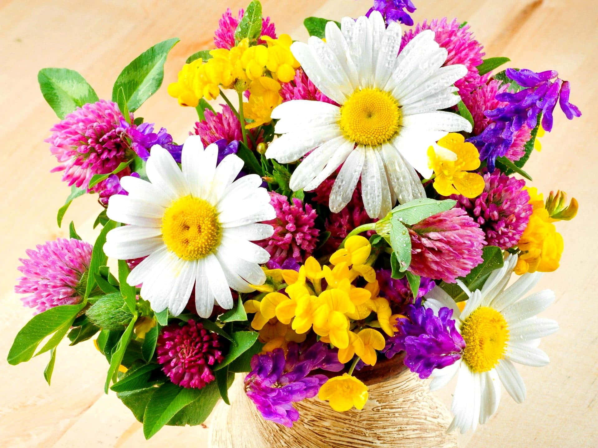 Delightful 桌布 壁紙 — 一個充滿活力的花束，包含白色雛菊、黃色三葉草和紫色花朵，放在木質表面上的編織籃子裡。