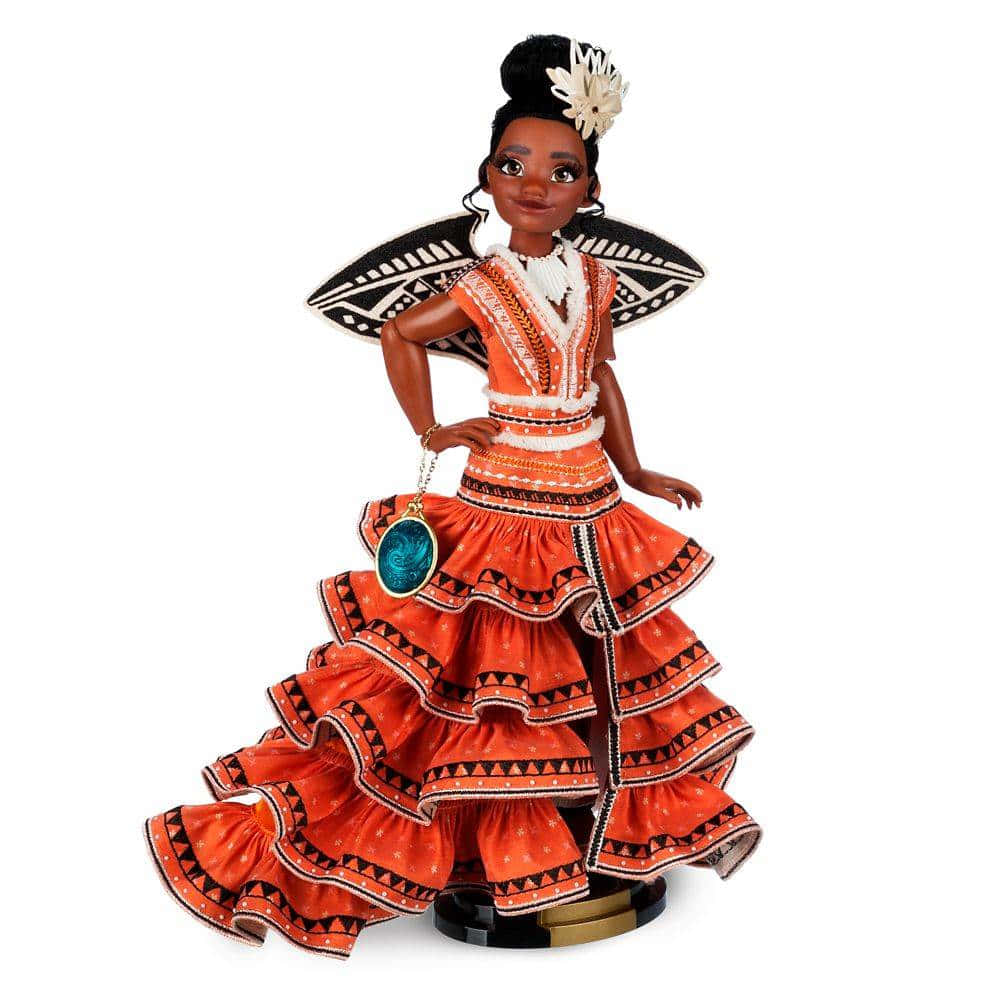 Moana 桌布 壁紙 — 一個充滿活力的莫阿娜娃娃，穿著傳統波利尼西亞服飾，帶有層疊的橙色荷葉邊和黑色幾何圖案，自信地站在純白色背景前。