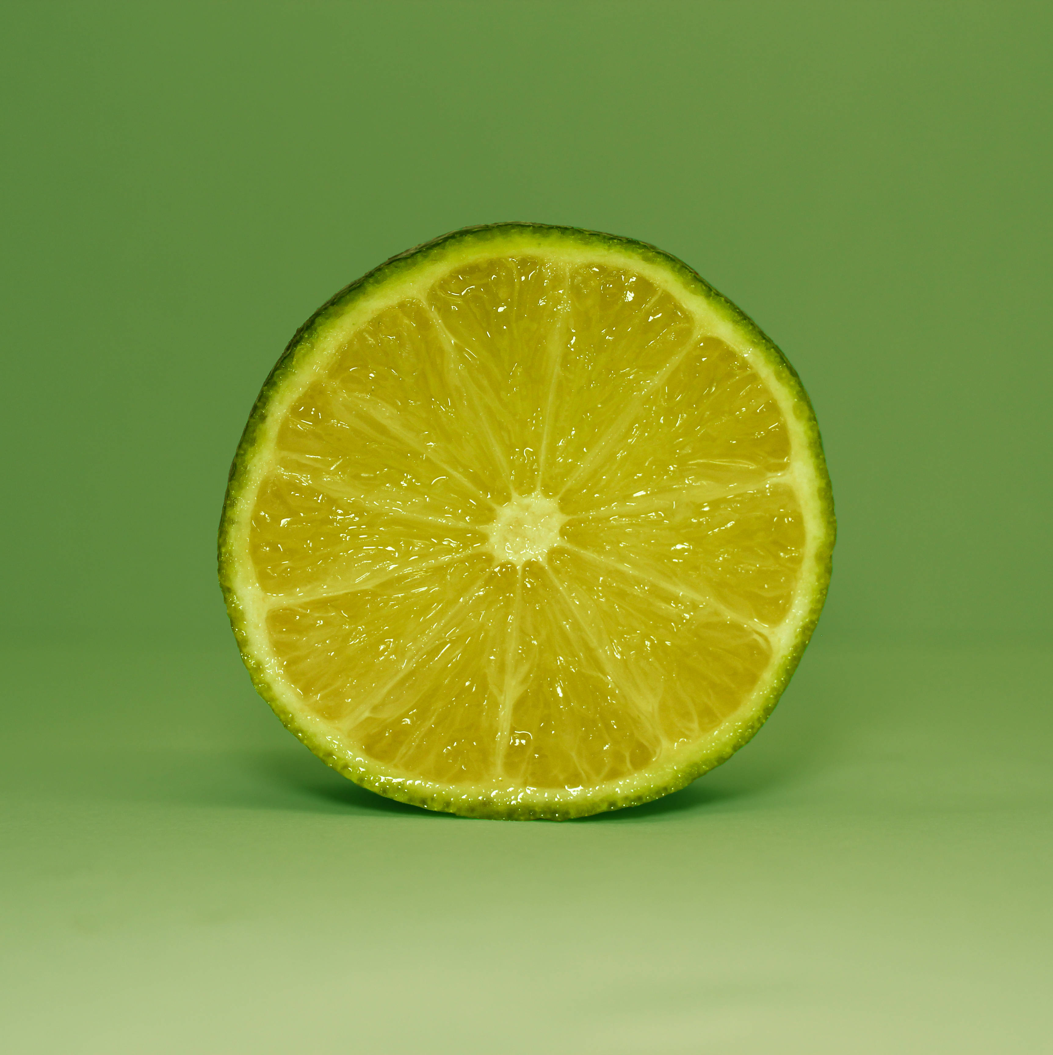 Fruit 桌布 壁紙 — 一個充滿活力的萊姆橫切面，在純綠色背景上展現多汁的果瓣。