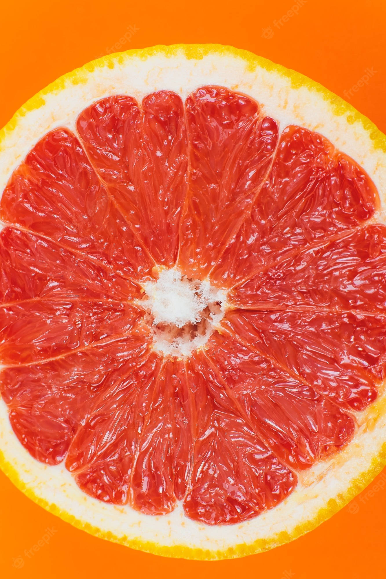 Fruit 桌布 壁紙 — 一個充滿活力的葡萄柚橫切面，在鮮明的橙色背景上展現出多汁的紅色果瓣。