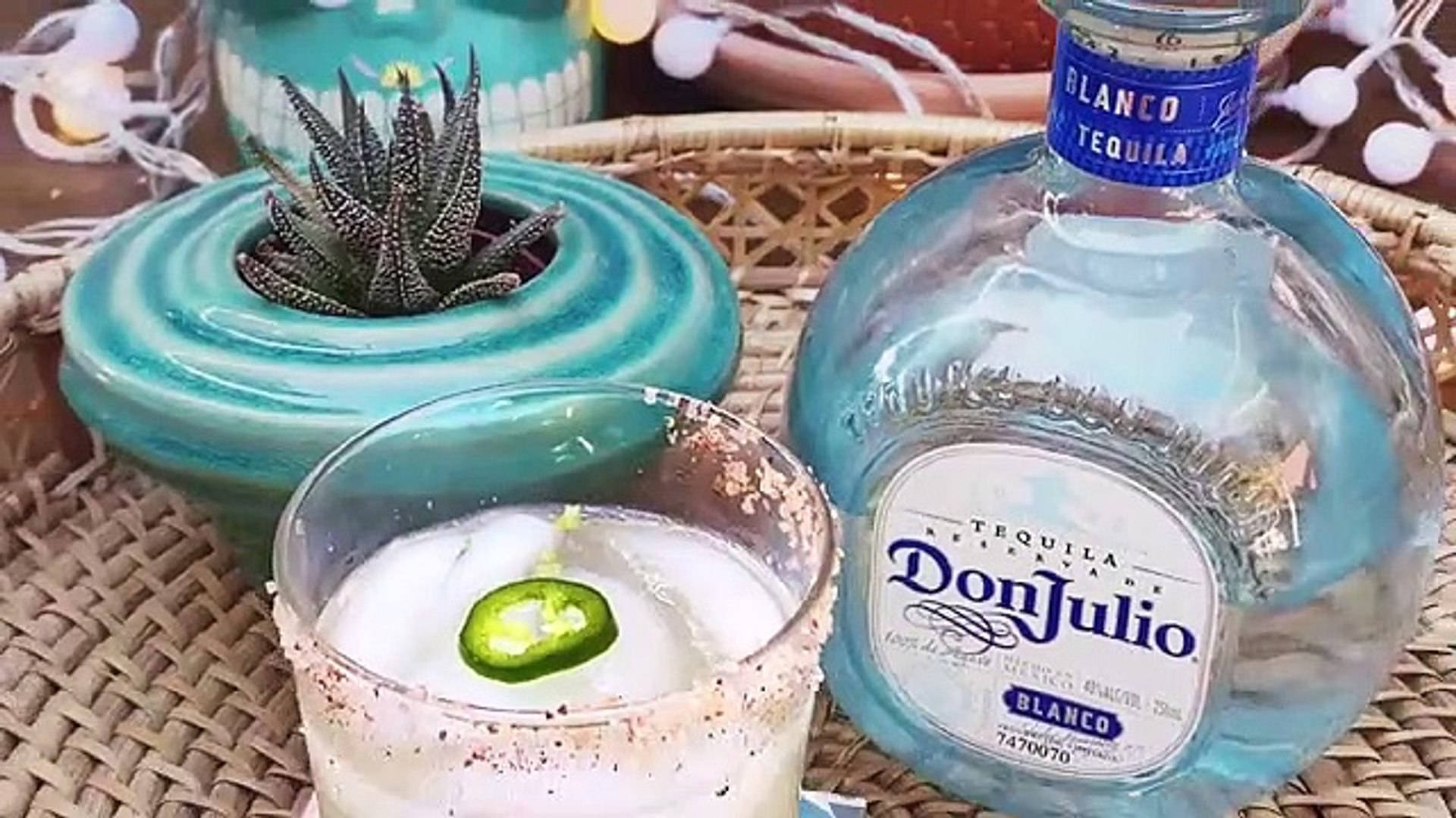 Drink 桌布 壁紙 — 一個充滿活力的藍色龍舌蘭酒瓶和帶有鹽邊和墨西哥辣椒裝飾的瑪格麗特酒，放在一個編織托盤上，旁邊是一個藍綠色的花盆，裡面種著多肉植物。