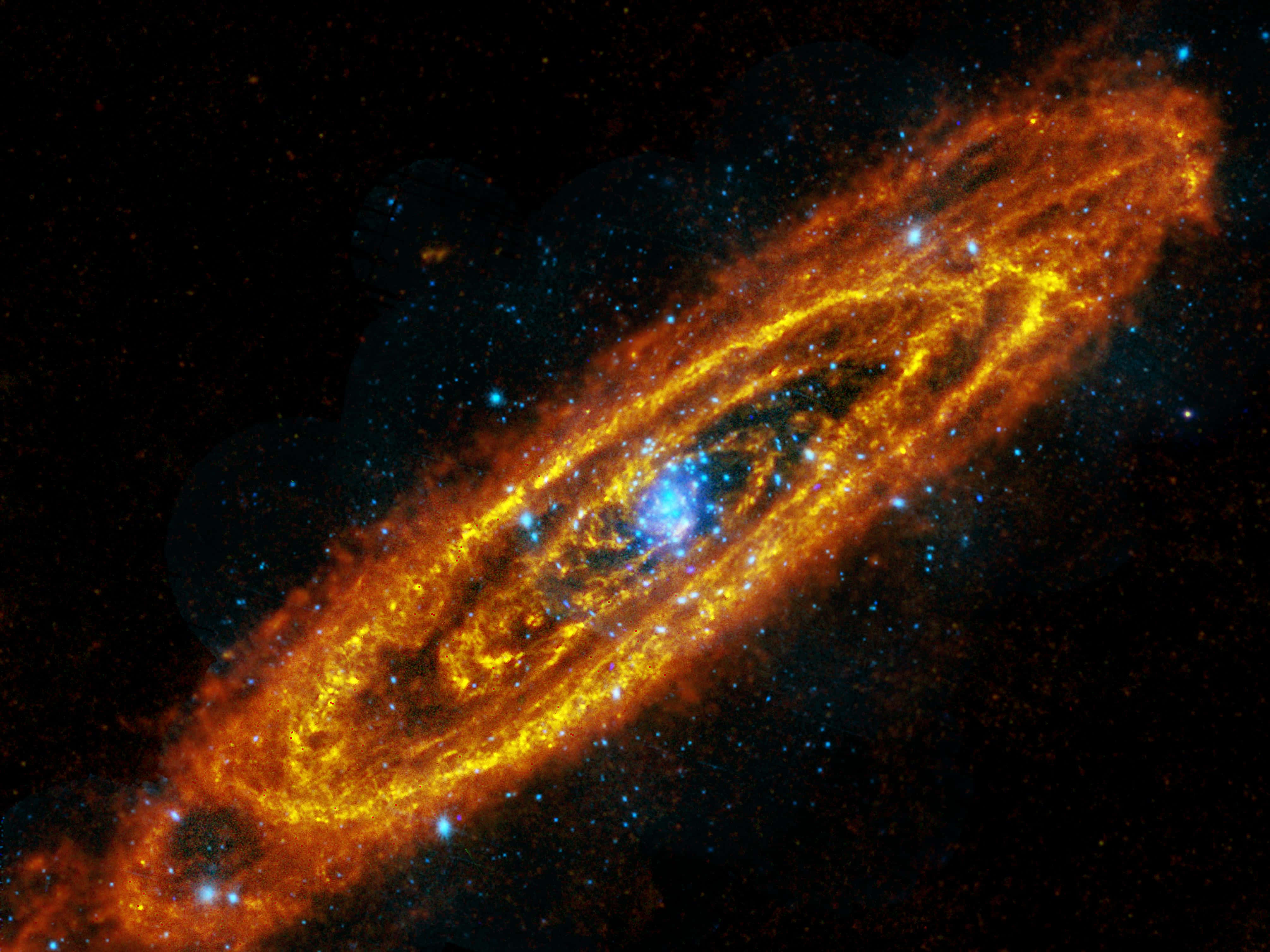 Nasa Galaxy 桌布 壁紙 — 一個充滿活力的螺旋星系，在佈滿星星的黑色虛空中，熾熱的橙色和金色旋臂圍繞著明亮的藍色核心旋轉發光。