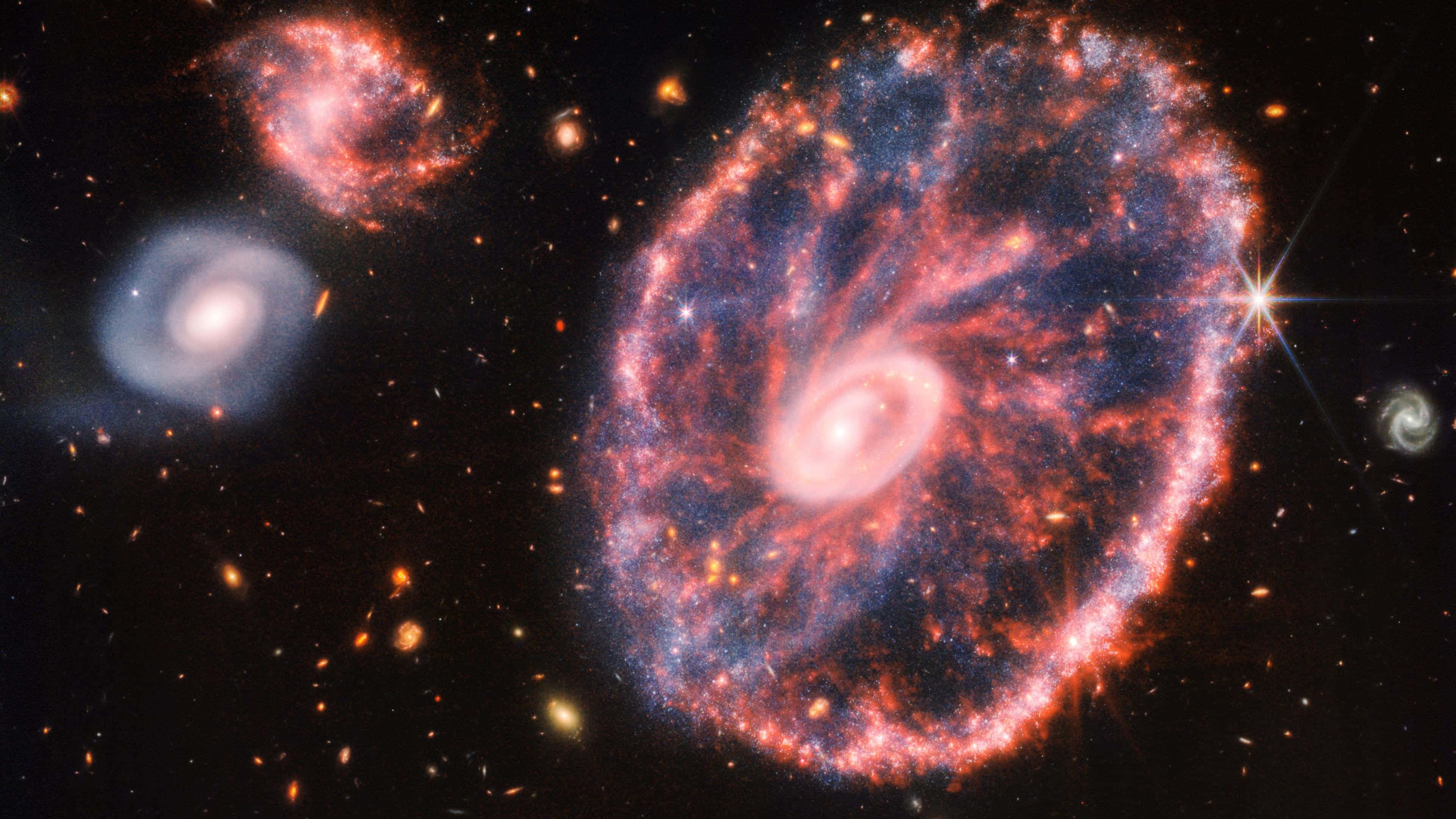 Telescope 桌布 壁紙 — 一個充滿活力的螺旋星系，帶有火紅和藍色的旋臂，在星場中旋轉，散發著宇宙能量。