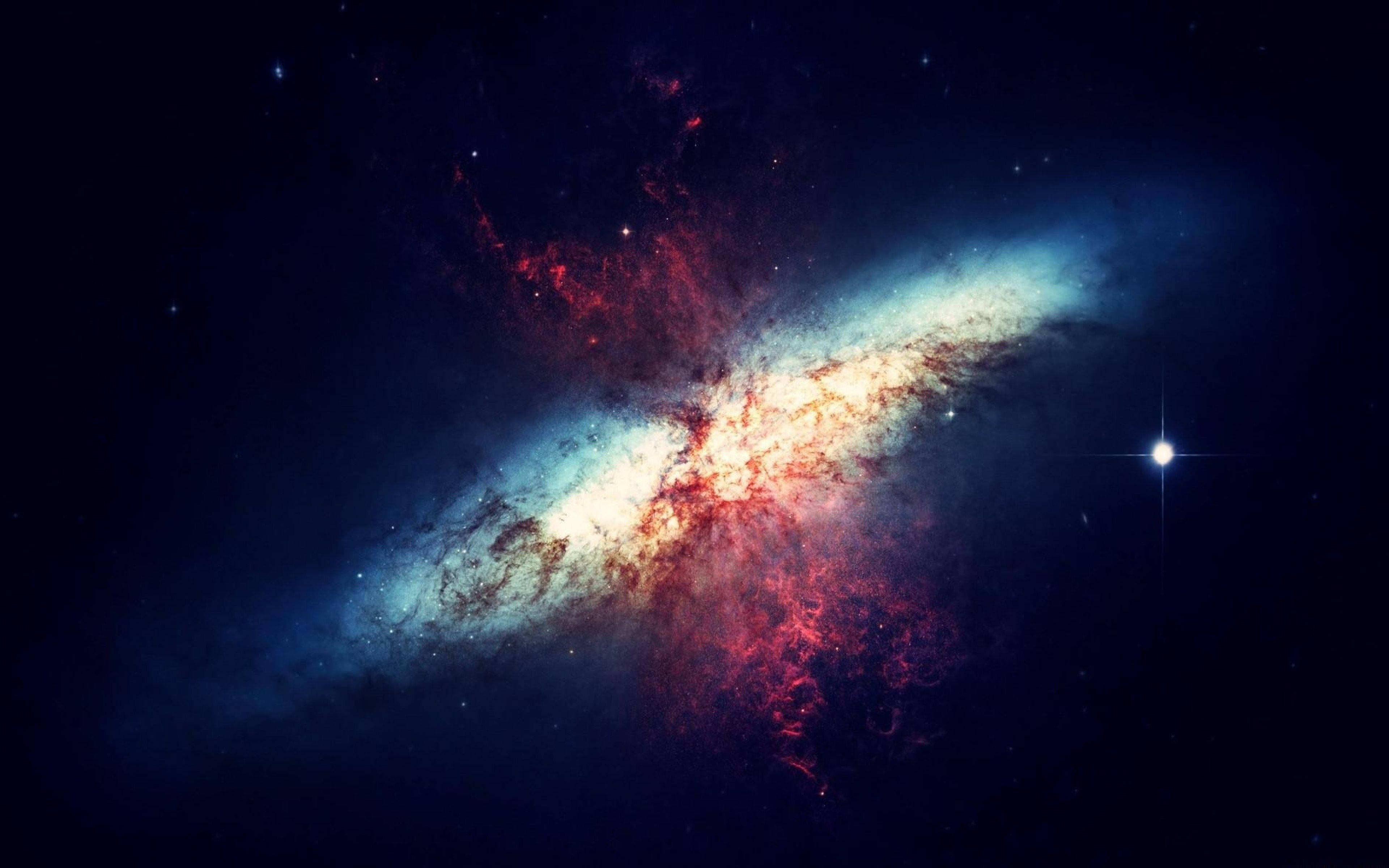 4K 太空 桌布 壁紙 — 一個充滿活力的螺旋星系在繁星點點的宇宙背景下發出紅色和藍色的星雲光芒。
