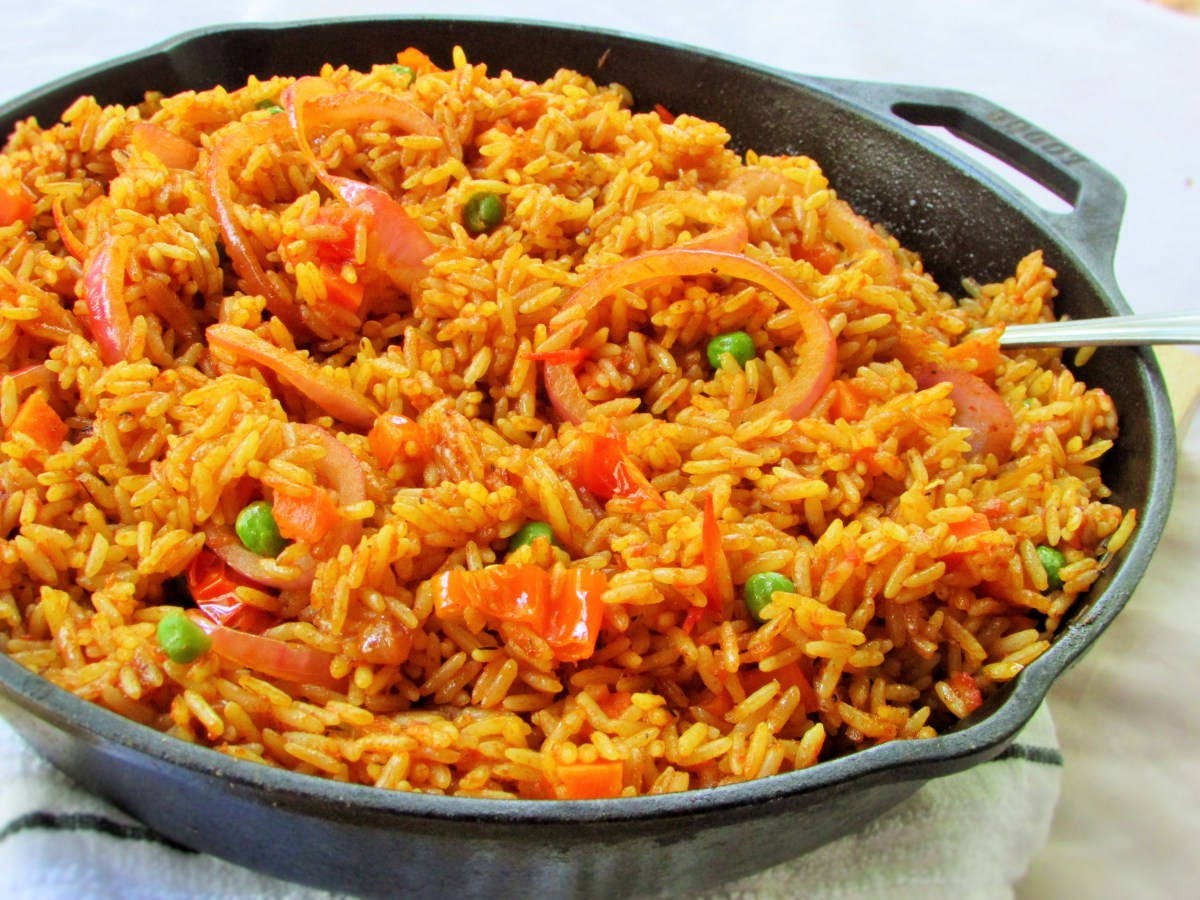 烹飪 桌布 壁紙 — 一個充滿活力的鑄鐵煎鍋，盛載著色彩繽紛的番紅花飯，混合了紅椒、洋蔥和青豆。