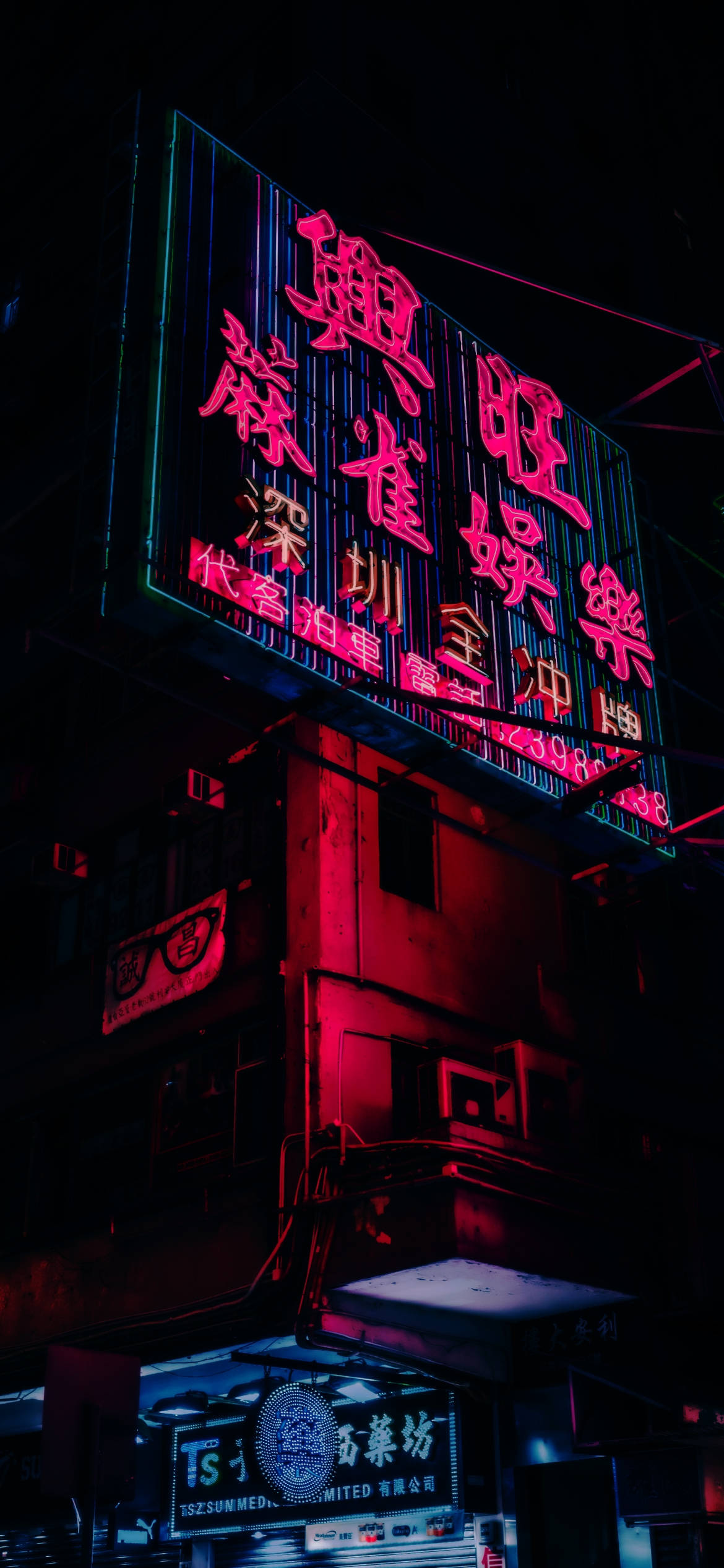 桌布 壁紙 — 一個充滿活力的霓虹燈牌在黑暗的城市夜空中發出紅色和綠色的光芒，在周圍的建築物上投射出色彩繽紛的倒影。
