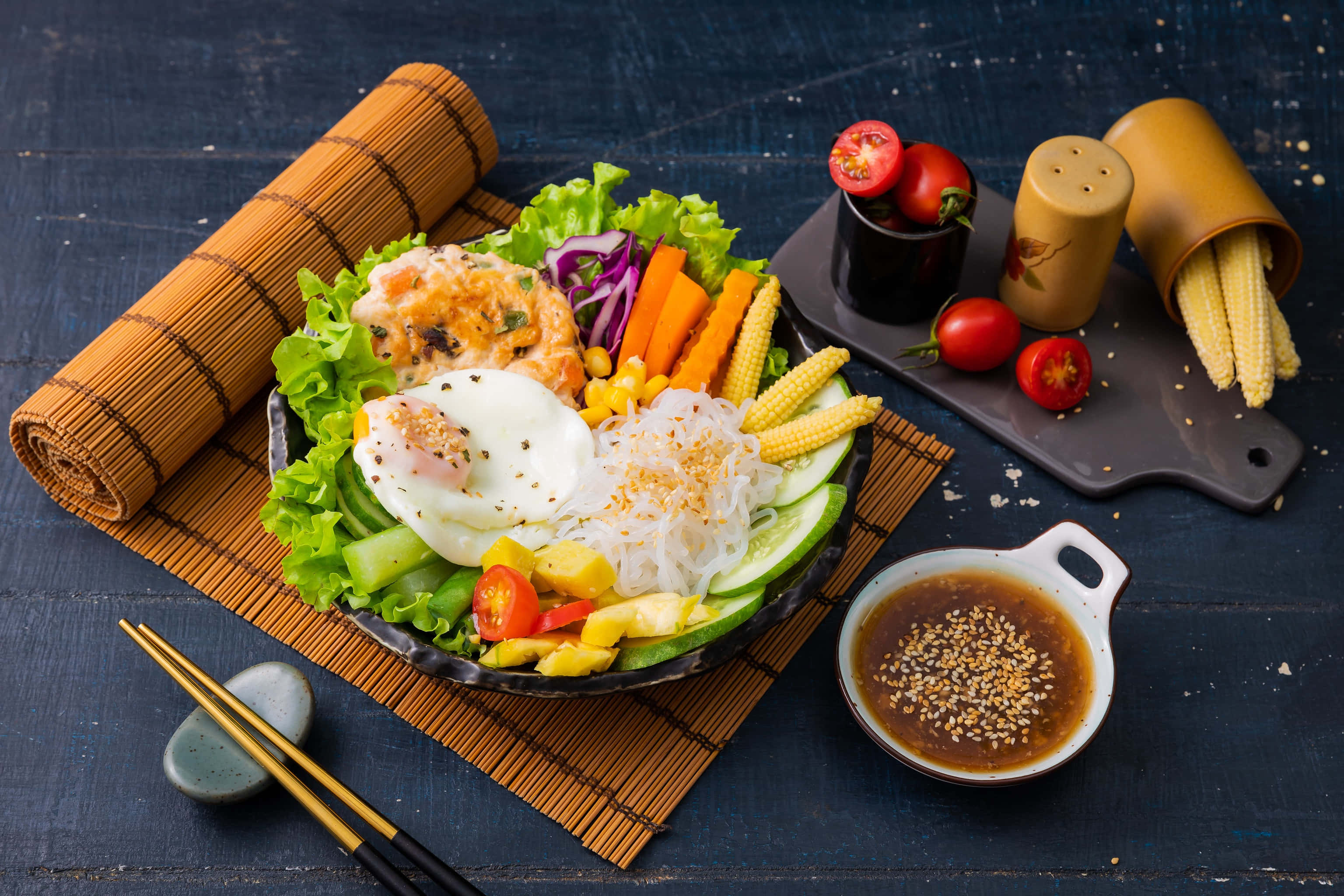 沙拉 桌布 壁紙 — 一個充滿活力的韓式拌飯，上面放有水煮蛋、玉米、紅蘿蔔和新鮮蔬菜，放在深色木桌上。