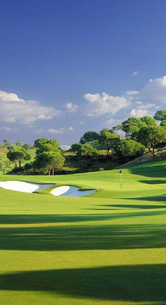 Pixel 3 Golf Course 桌布 壁紙 — 一個充滿活力的高爾夫球場，擁有鬱鬱蔥蔥的綠色球道和沙坑，在明亮的藍天和蓬鬆的白雲下。